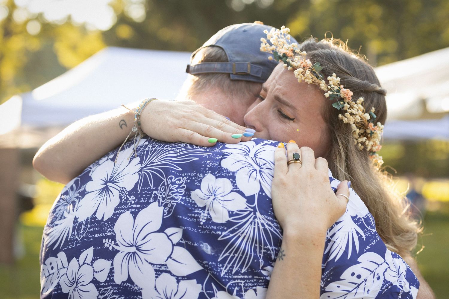 A romantic couple embraces on their wedding day wearing blue and white floral Hawaiian matching outfits at sunset.