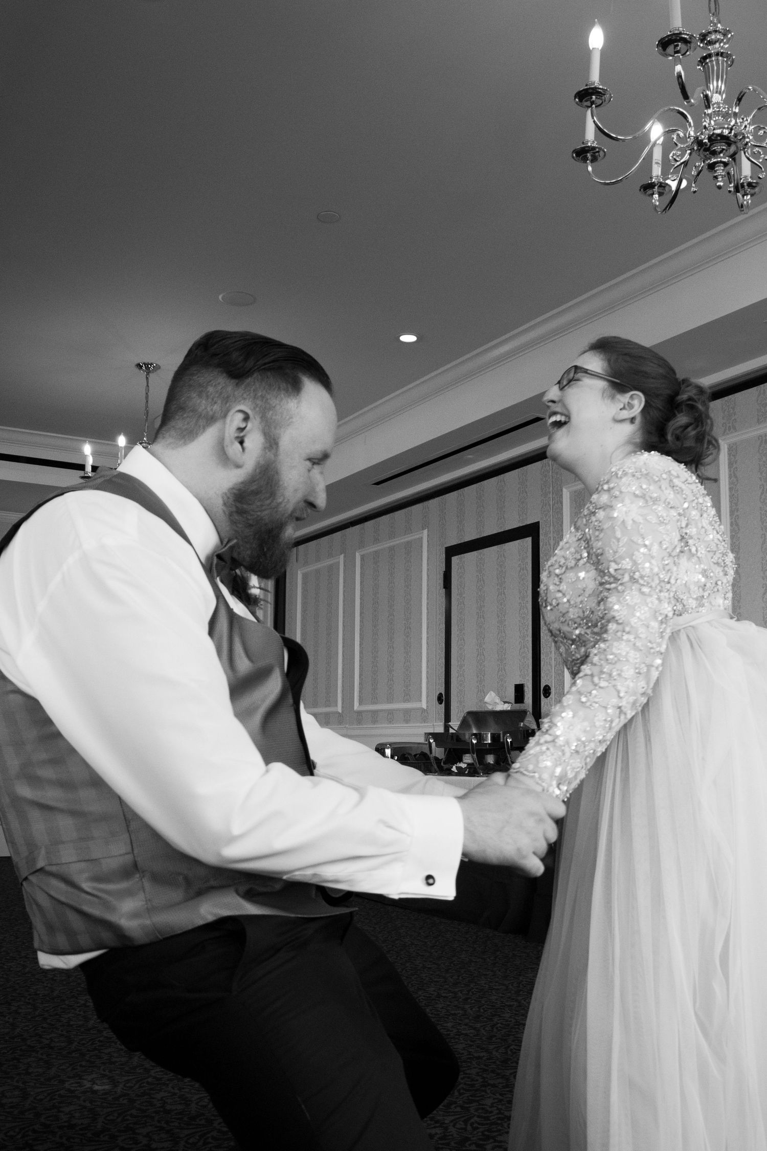 A couple shares an emotional first dance moment at their wedding reception in a black and white photograph.