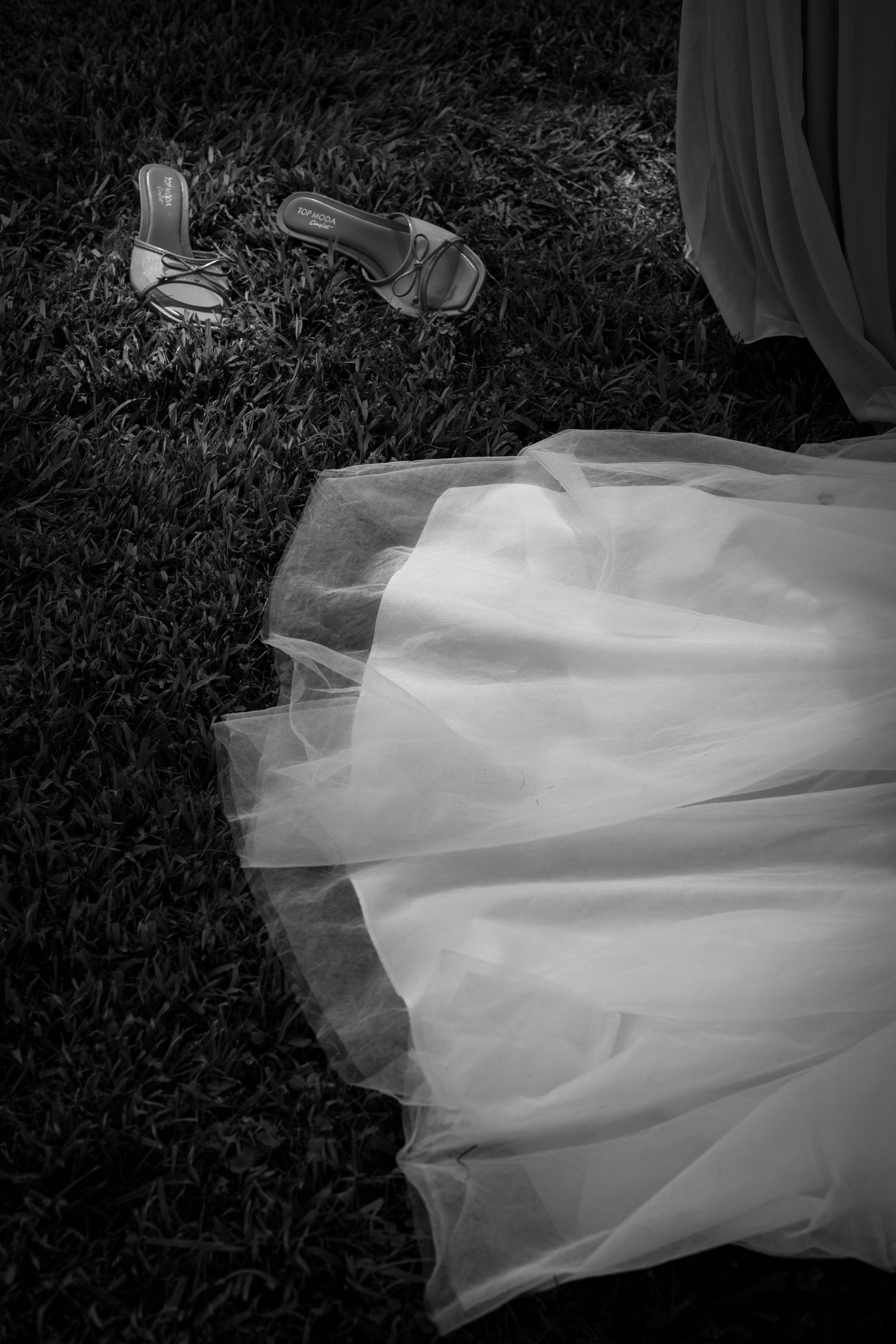 Flowing white tulle wedding dress fabric skirt shown in cascading movement against dark grass backdrop in a series of images.