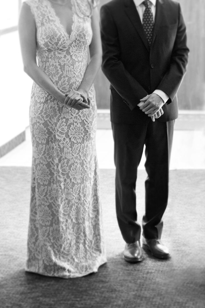 Black and white detail shots of formal dress hem and shoes during wedding ceremony with elegant lace details and dark suits.