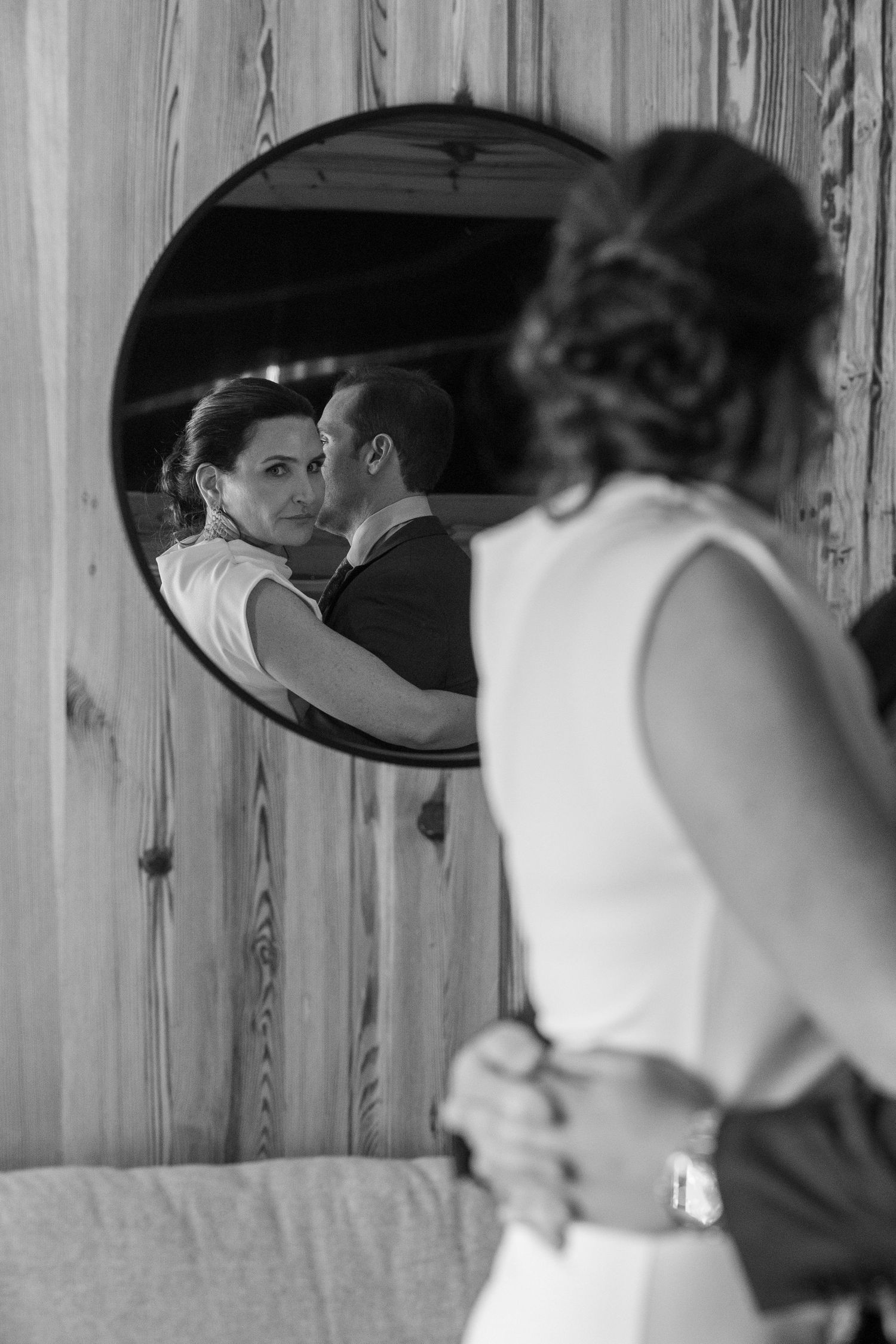 Artistic black and white reflection in mirror shows couple embracing during romantic moment.