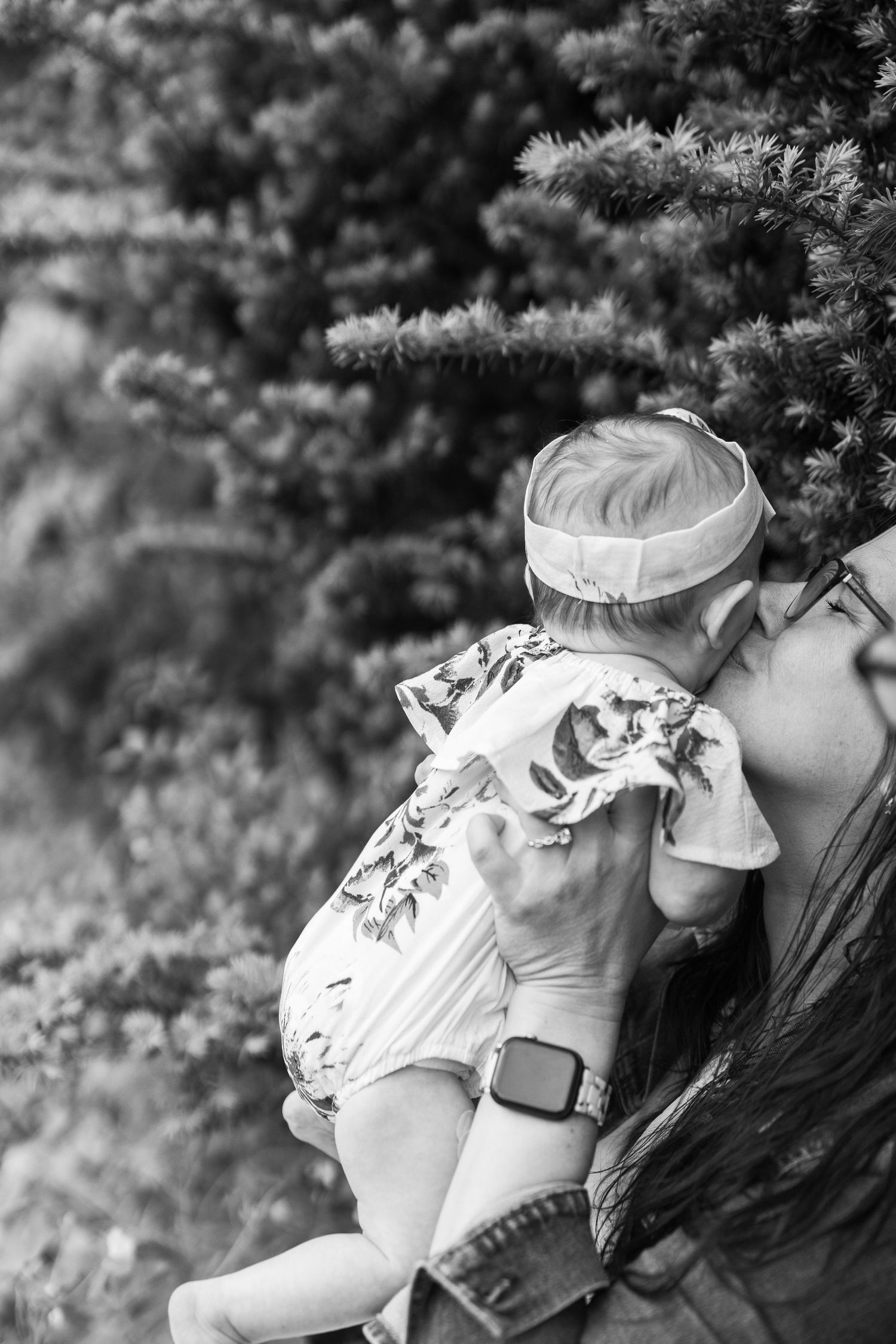 A black and white photograph showing two people in profile sharing a tender romantic moment outdoors.