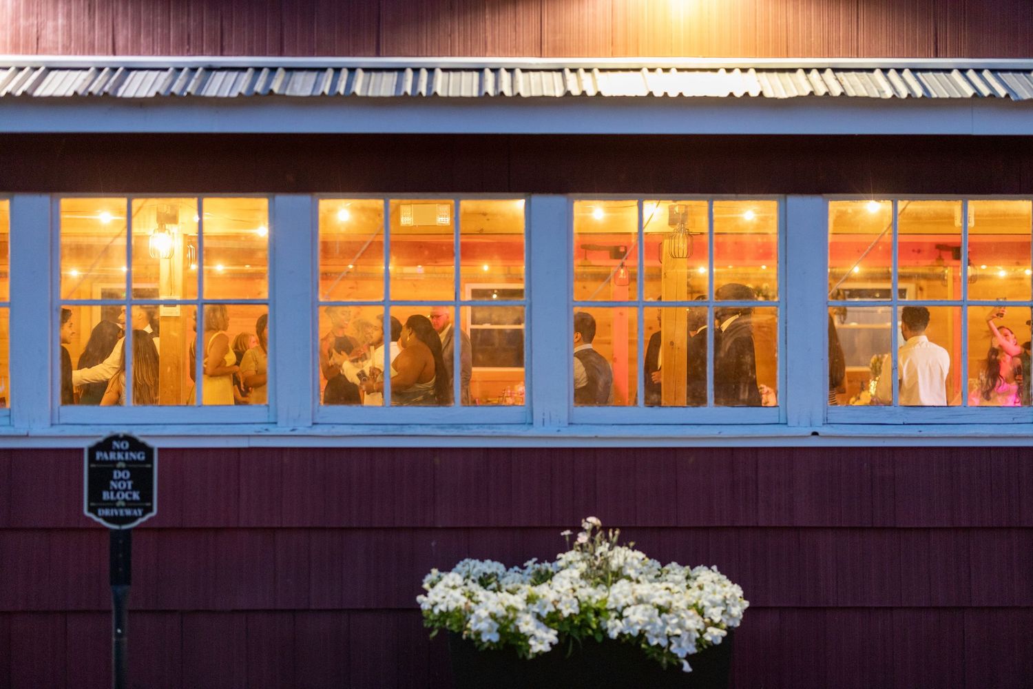 Sunset light illuminates a row of illuminated train car windows against a dark maroon exterior.