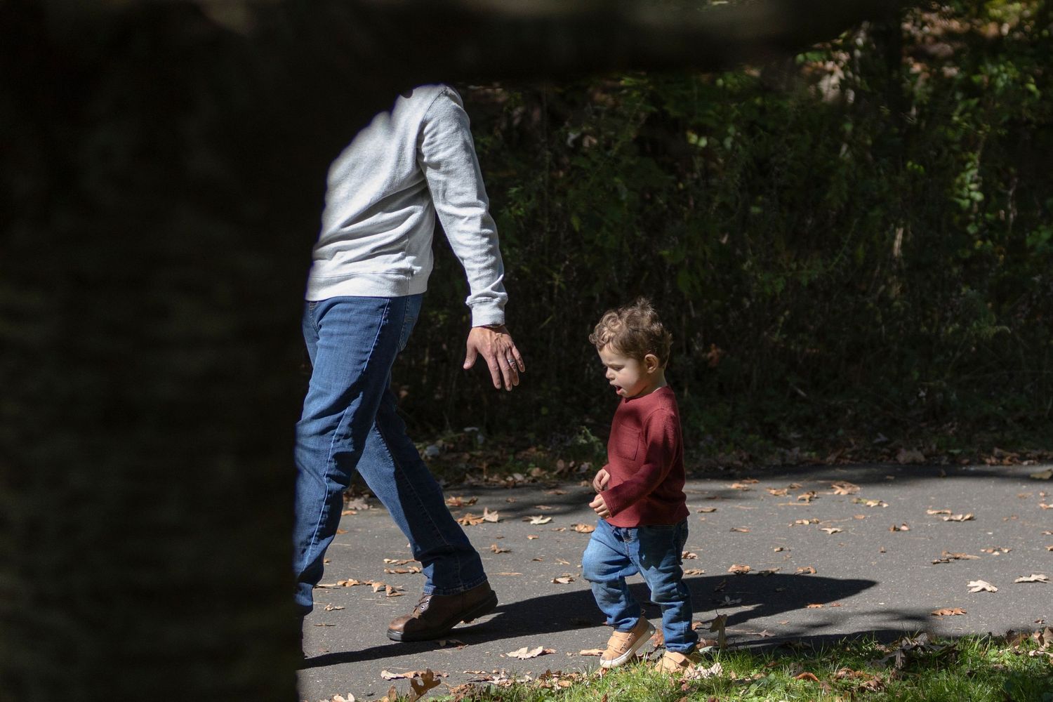 Parent and child enjoying an autumn day together playing with fallen leaves in the park.