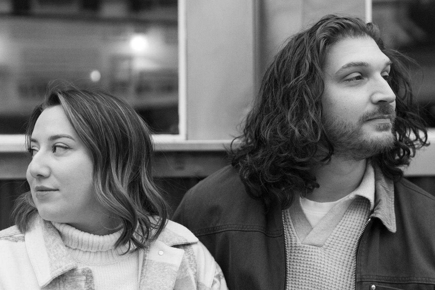 Black and white portrait of two people sitting together, with one looking left and the other looking right.