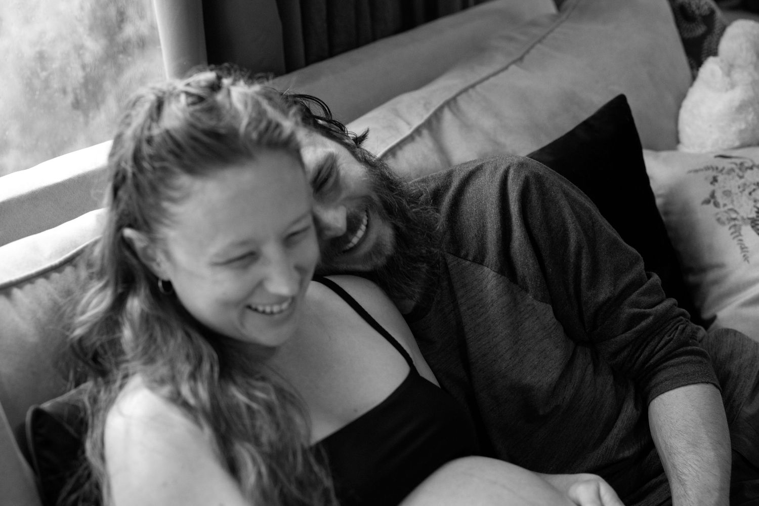 A candid black and white photo showing two people laughing together in a joyful moment.
