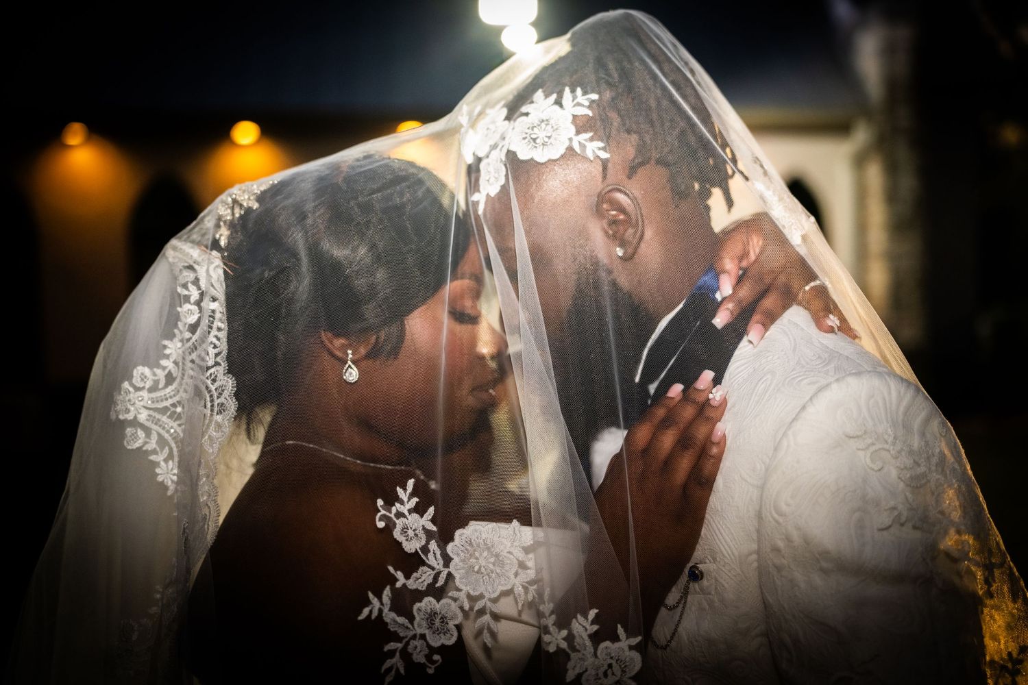 An intimate moment under a lace veil during a wedding ceremony.