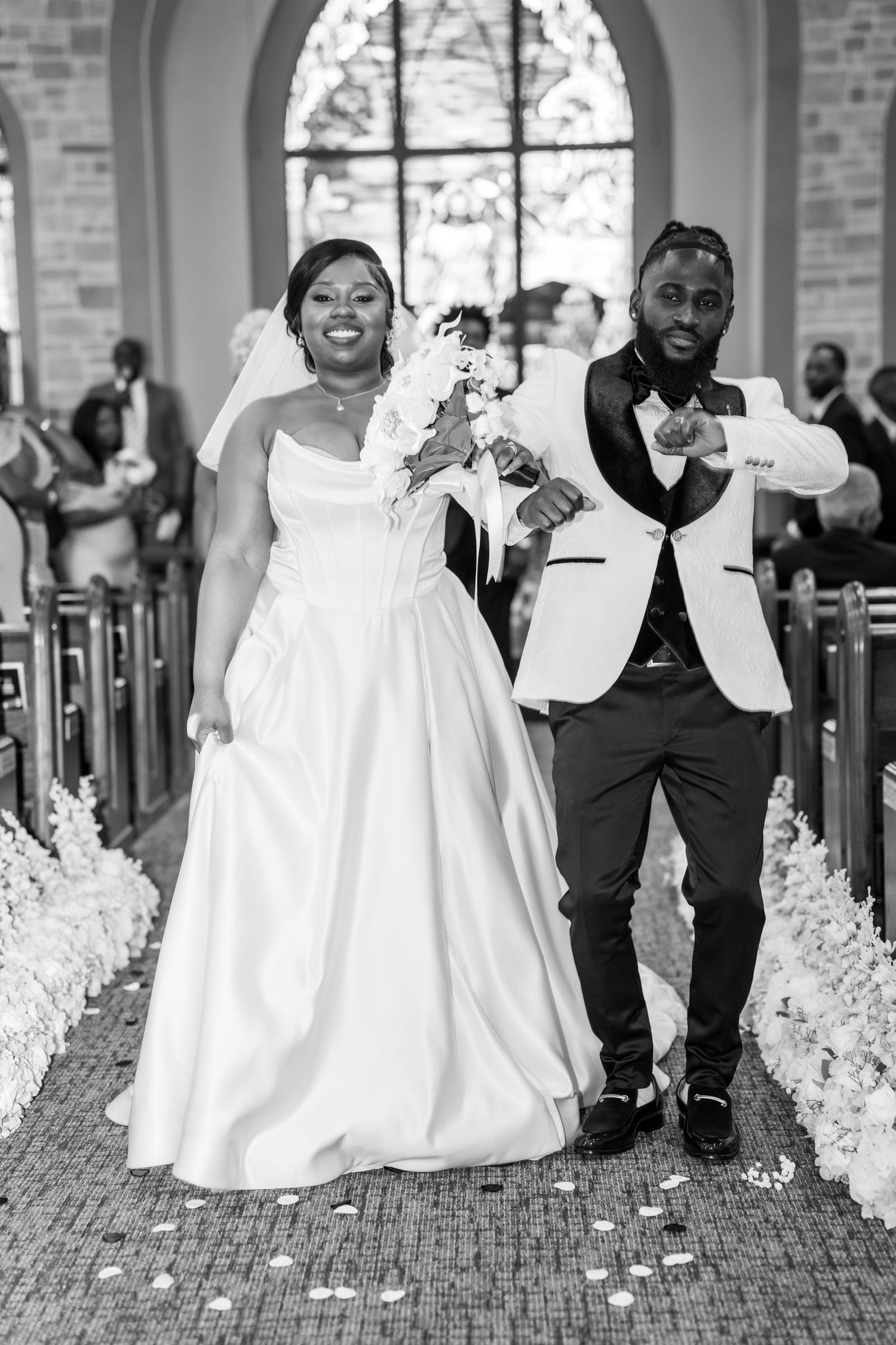 A joyful wedding ceremony exit with celebratory poses in a church aisle.