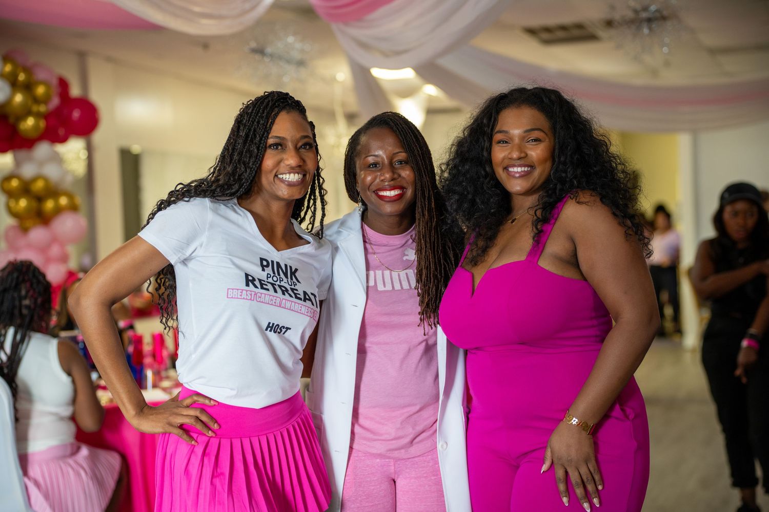 Three guests in coordinating pink outfits celebrate at a festive party.