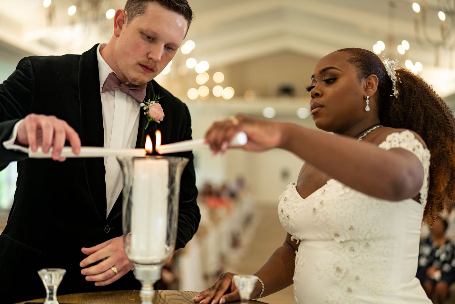 Newlywed couple lighting a unity candle together during their elegant wedding ceremony reception.