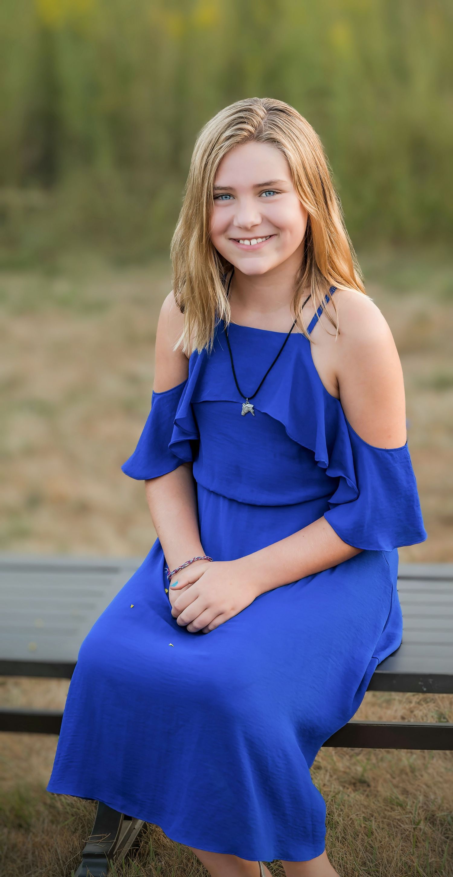 A portrait photo shows a bright blue cold-shoulder dress against a natural outdoor background.