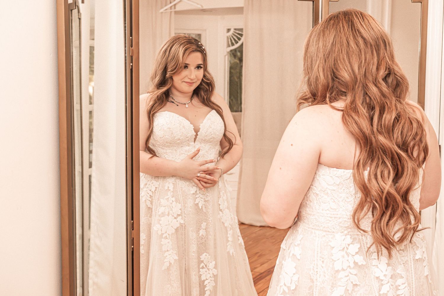 Beautiful wedding dress reflection scene with lace details and flowing skirt in a softly lit dressing room.