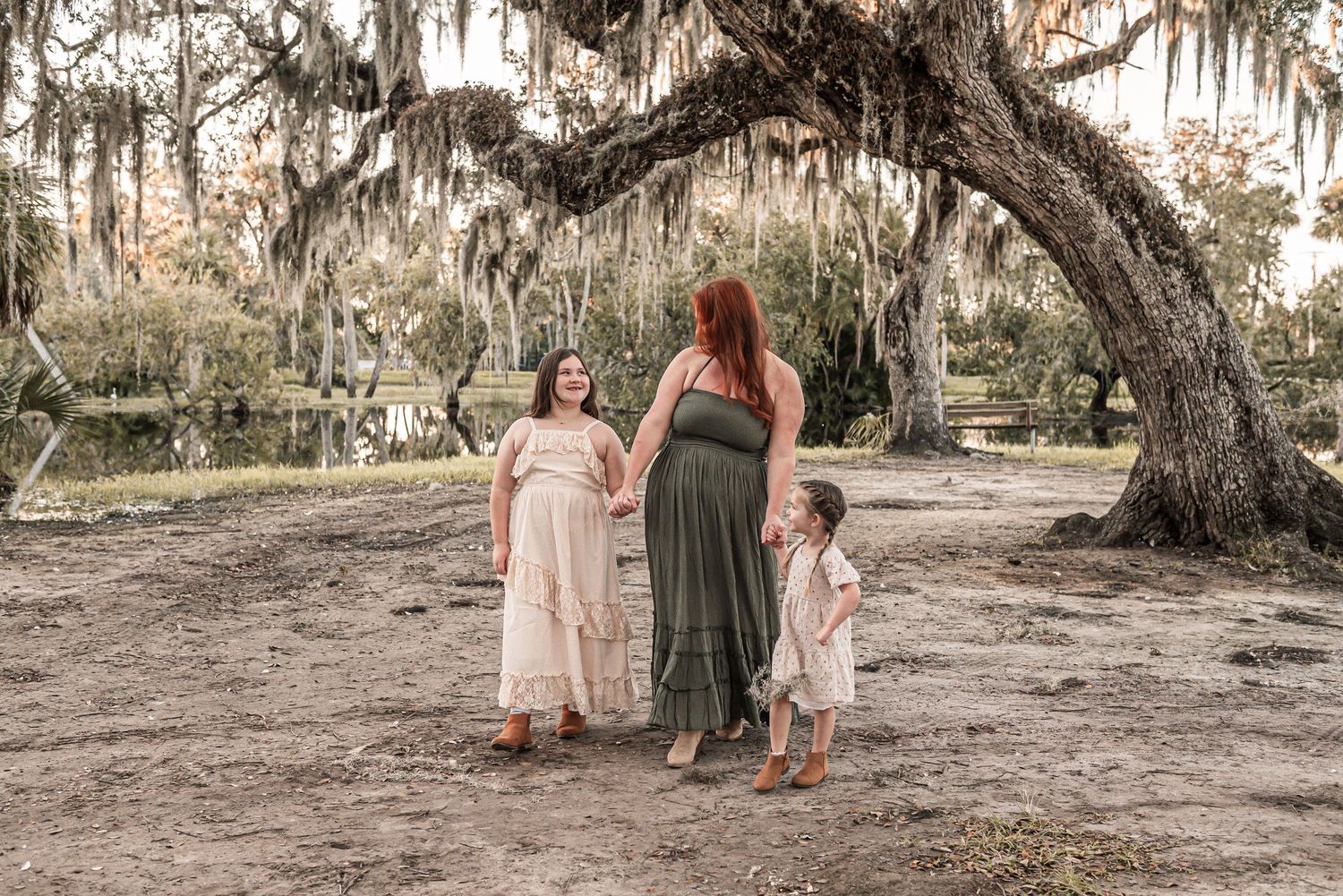 Group in flowing maxi dresses poses together under Spanish moss hanging from oak trees.