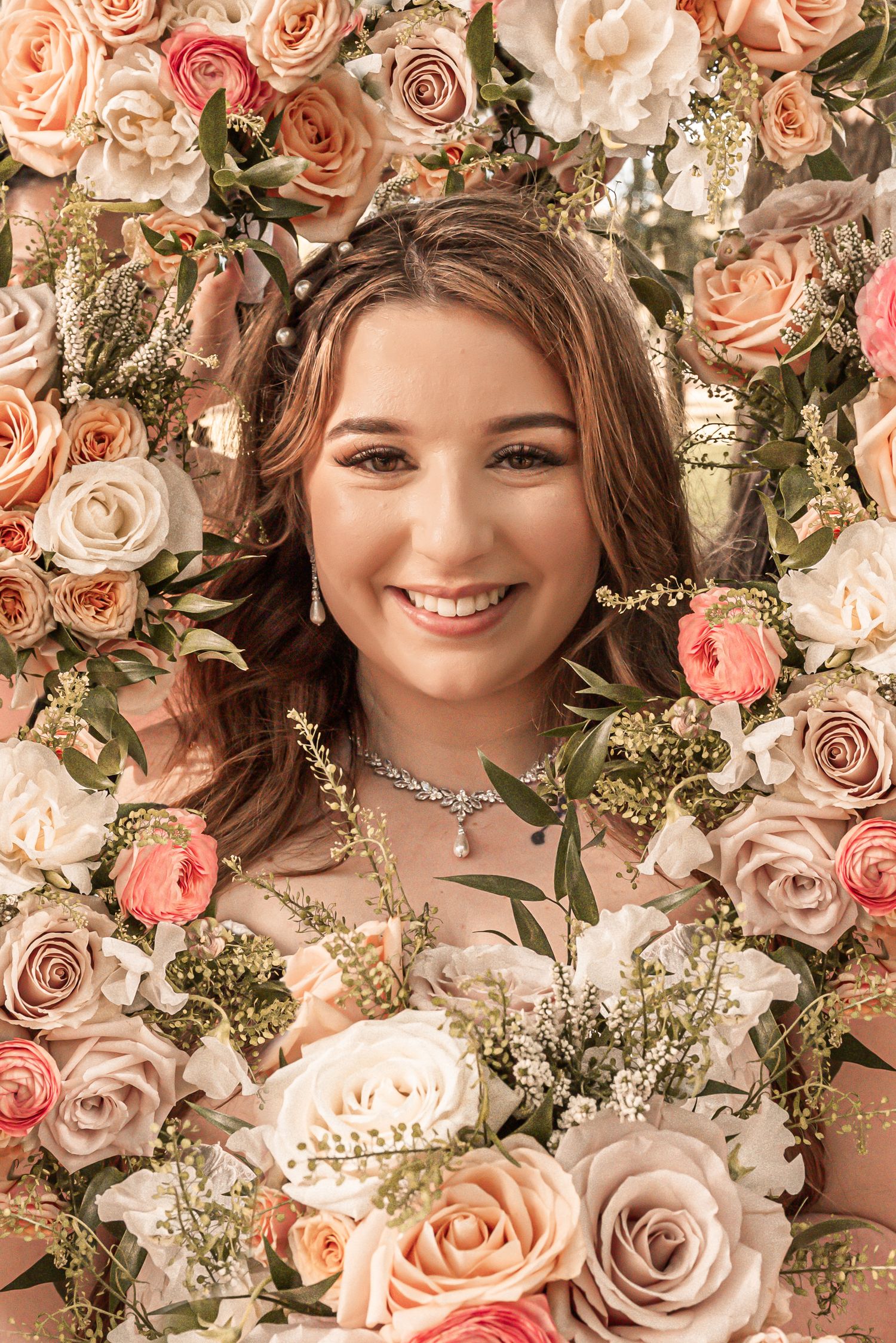 Beautiful portrait surrounded by elegant peach and blush roses with delicate greenery and baby's breath floral backdrop.