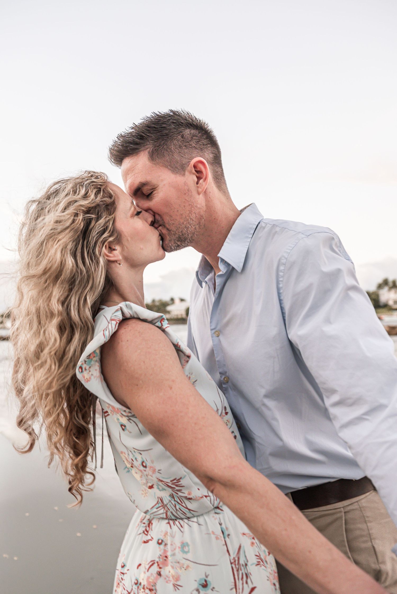 A romantic moment between a couple at sunset with her floral dress and his light blue button-down shirt.