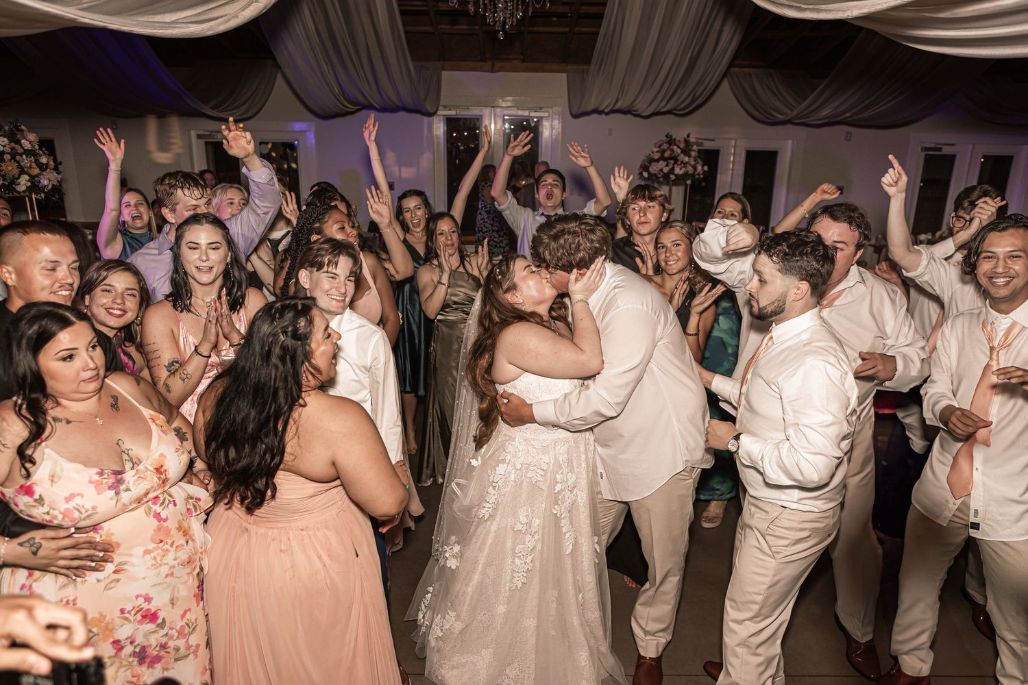 Wedding reception dance party with guests celebrating on the dance floor at an elegant indoor venue.
