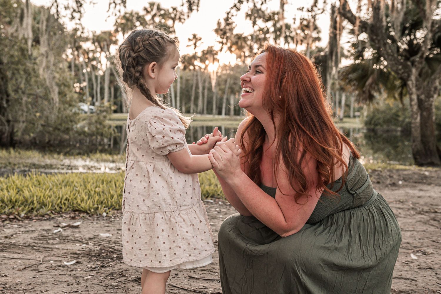 Two people share a heartwarming moment outdoors while wearing casual dresses in natural lighting.