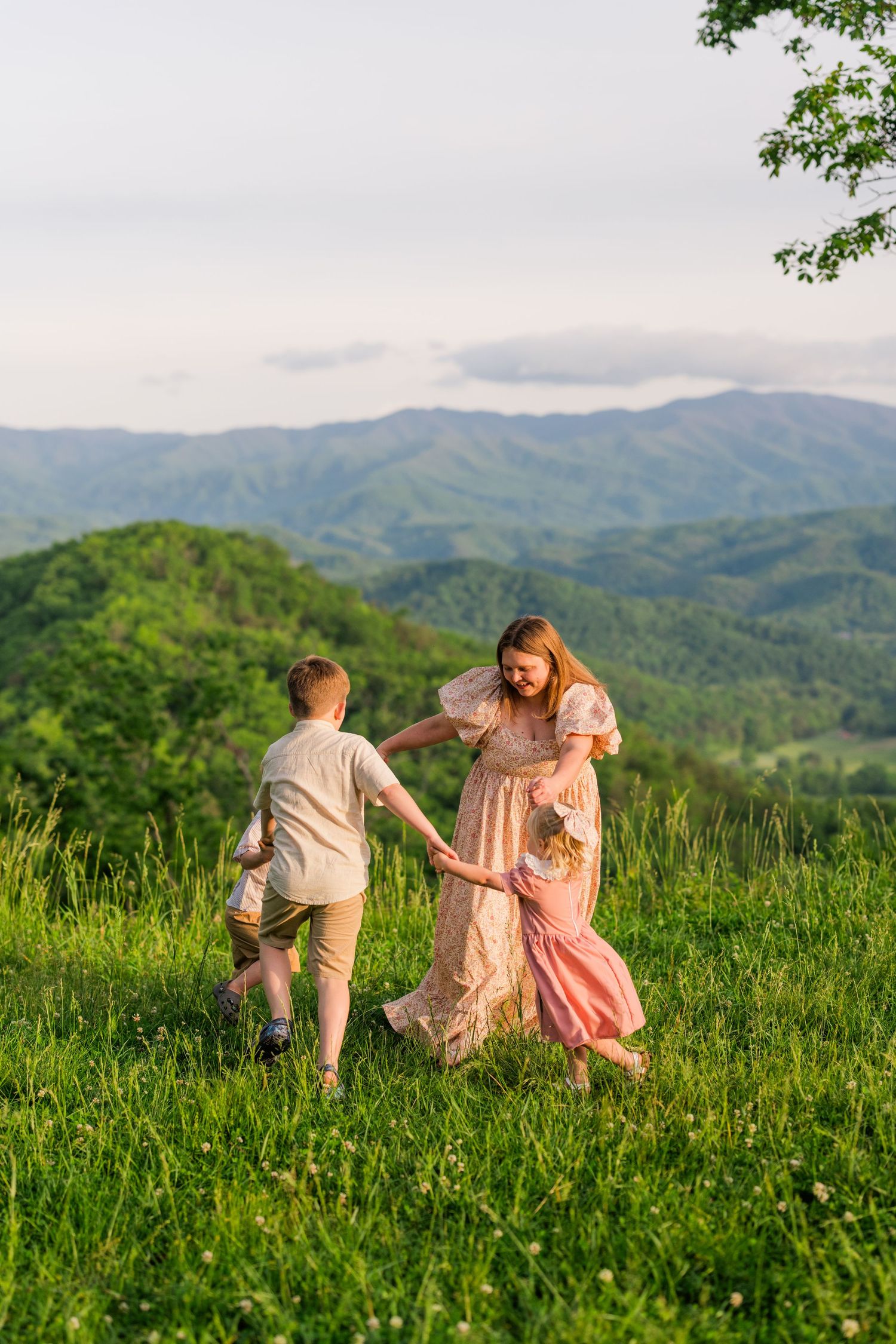 A family walks together through a lush mountain meadow on a summer evening in the rolling green hills.