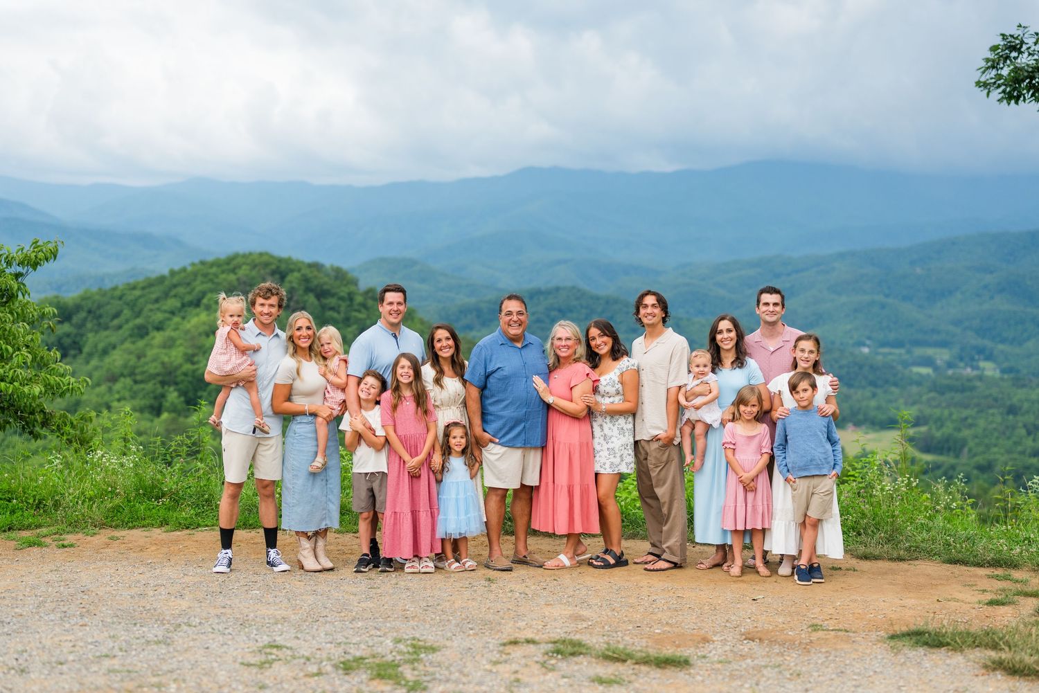 A large group enjoys a summer day on a mountain overlook with a scenic blue ridge mountain vista in the background.