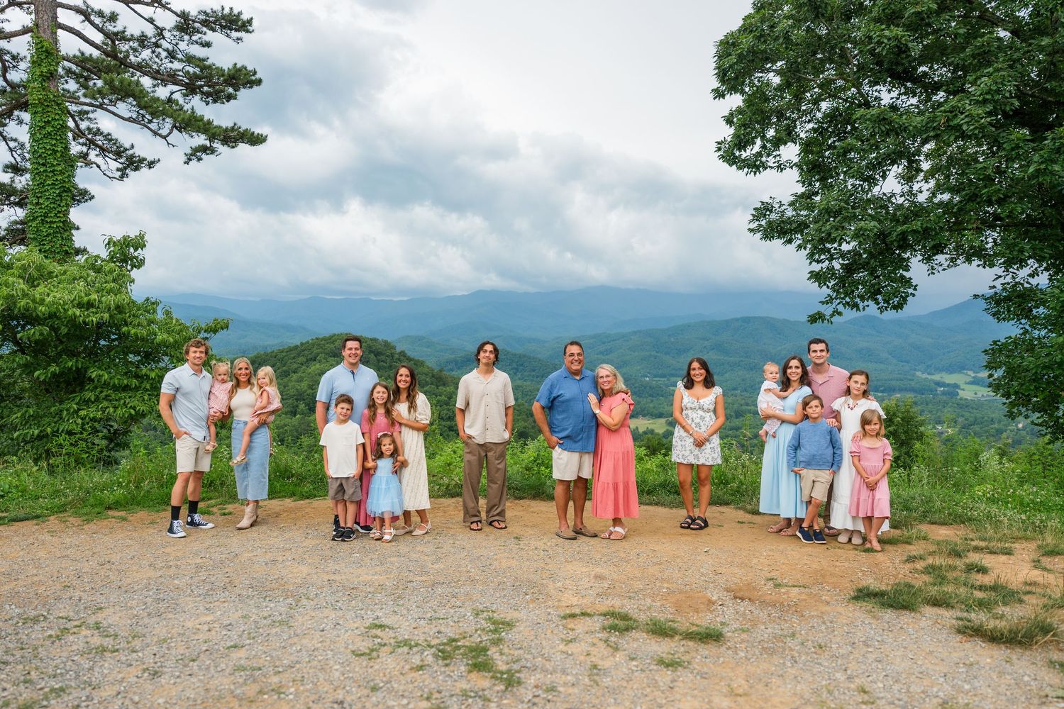 A group standing together on a scenic mountain overlook during a summer gathering with green trees and cloudy skies.