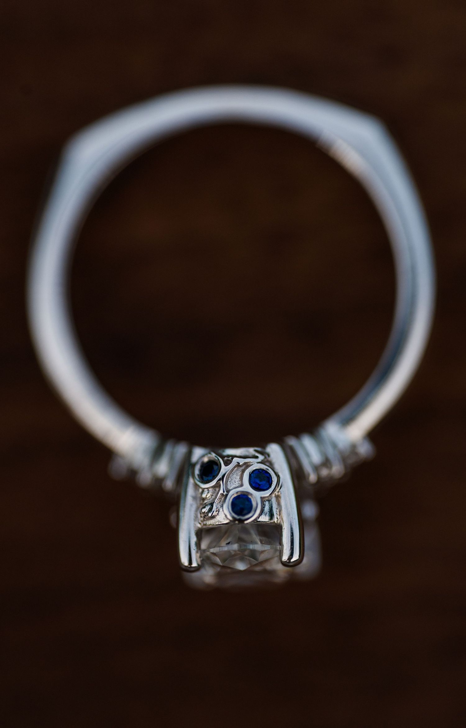 A series of close-up photos showing different angles of a sapphire and silver engagement ring on a dark background.