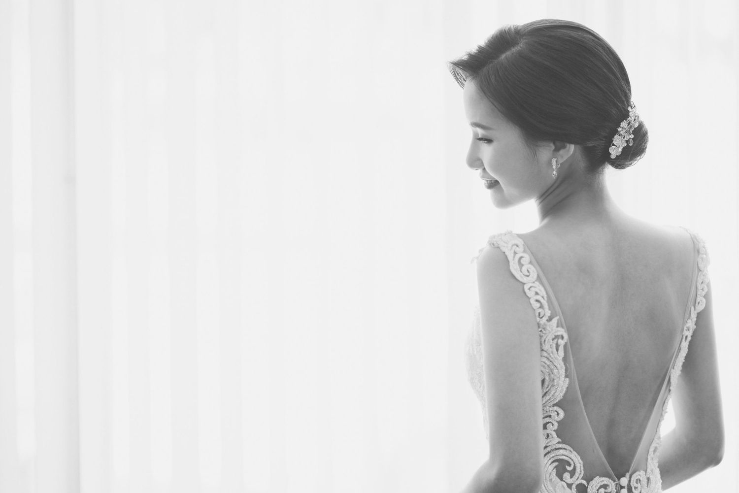 A bride in a delicate white lace gown poses elegantly by a window in three different angles.
