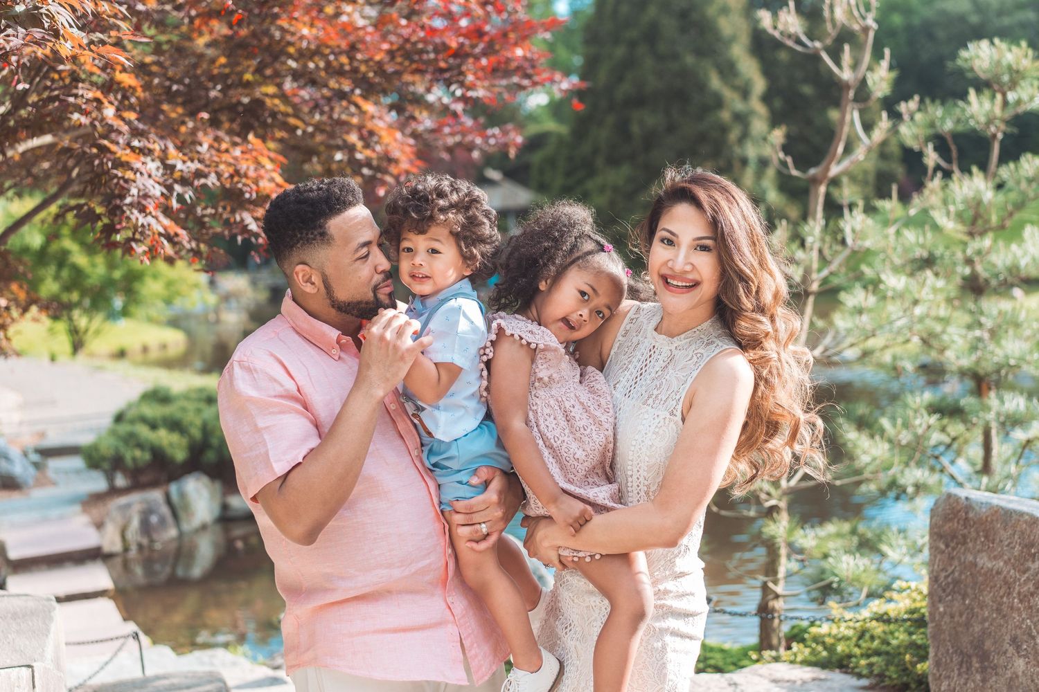 Happy family posing together in a garden with autumn foliage.