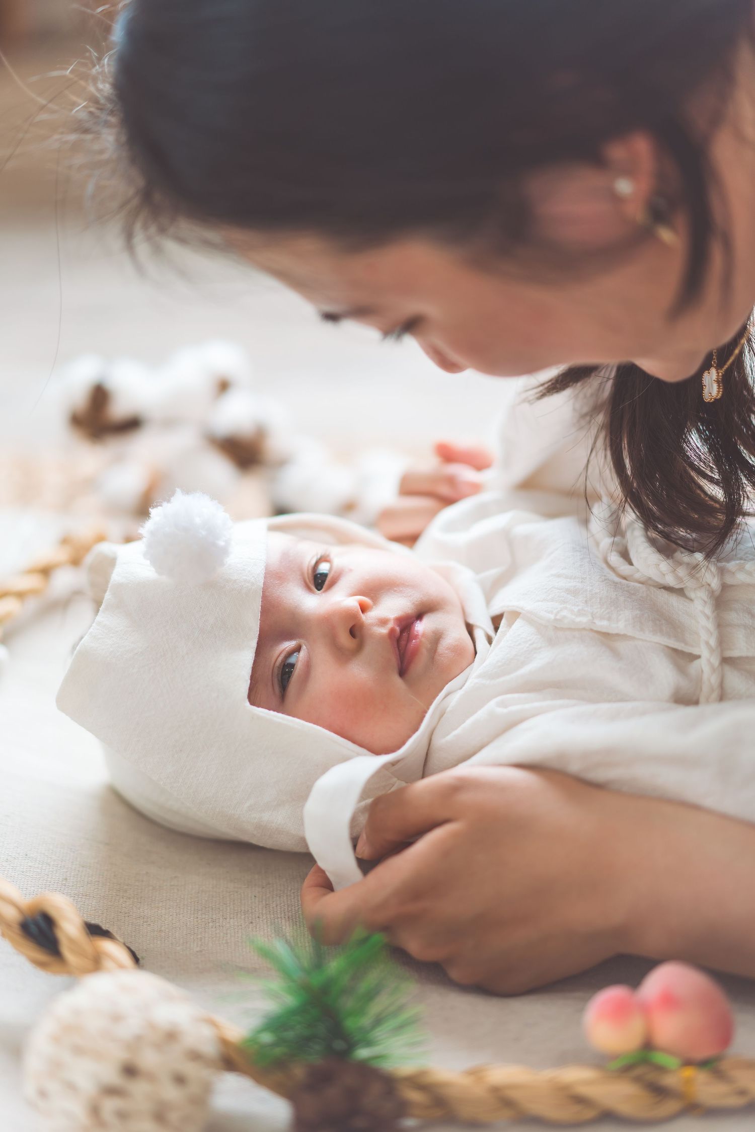 Tender moment between parent and baby lying on white blanket with decorative elements.