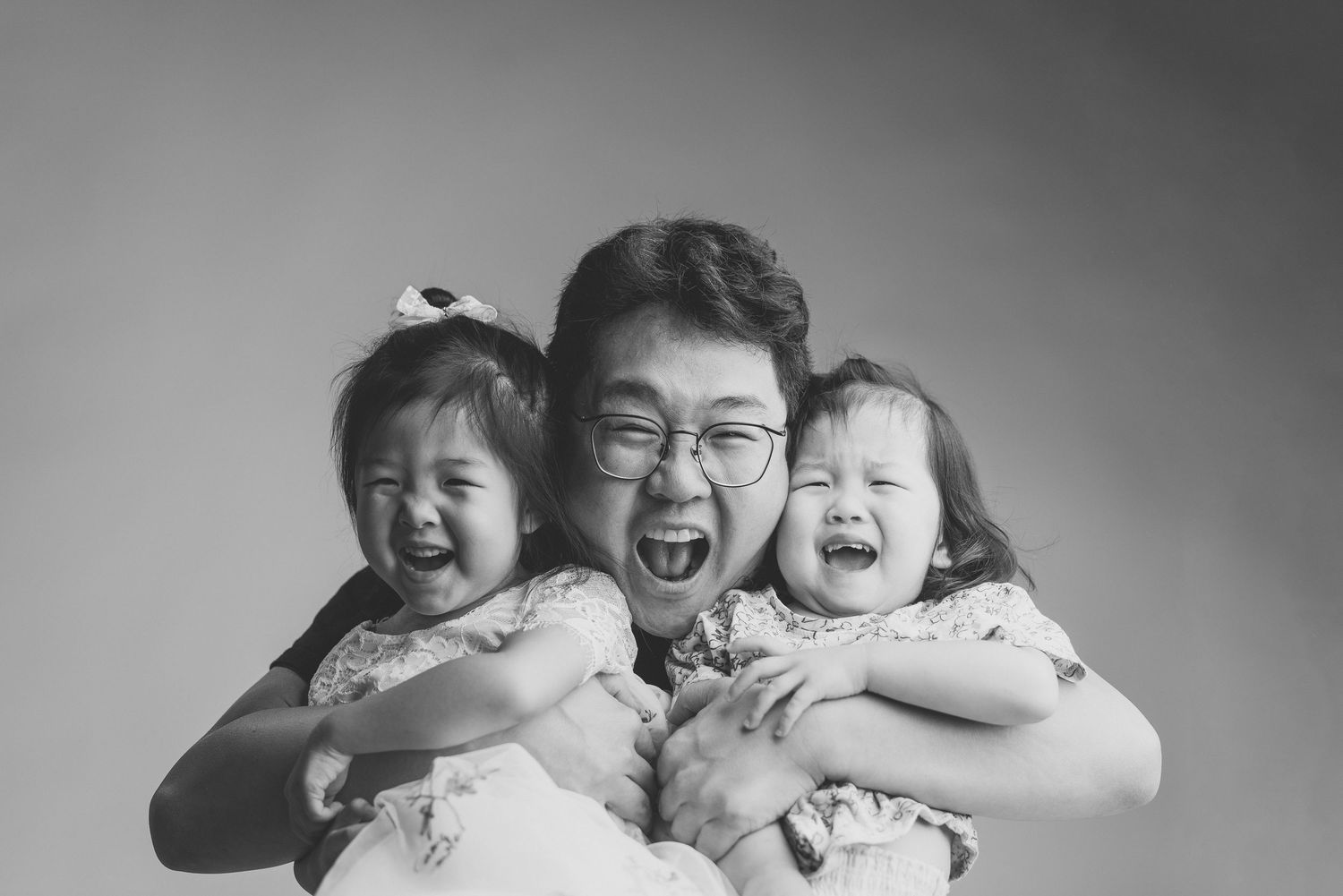 Family portrait series showing joyful expressions and laughter in black and white.