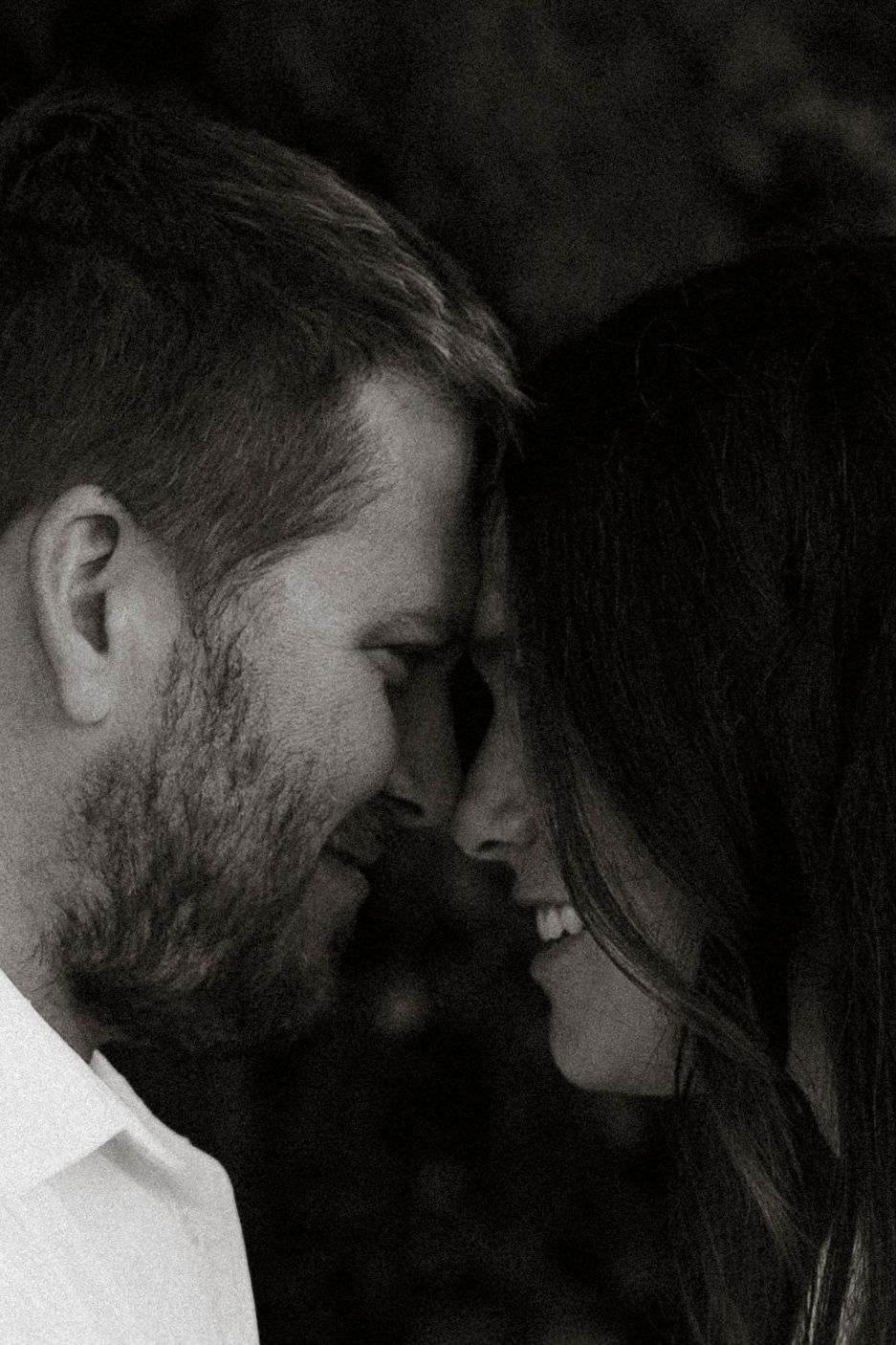 Close-up silhouettes of a romantic couple embracing in moody black and white lighting.