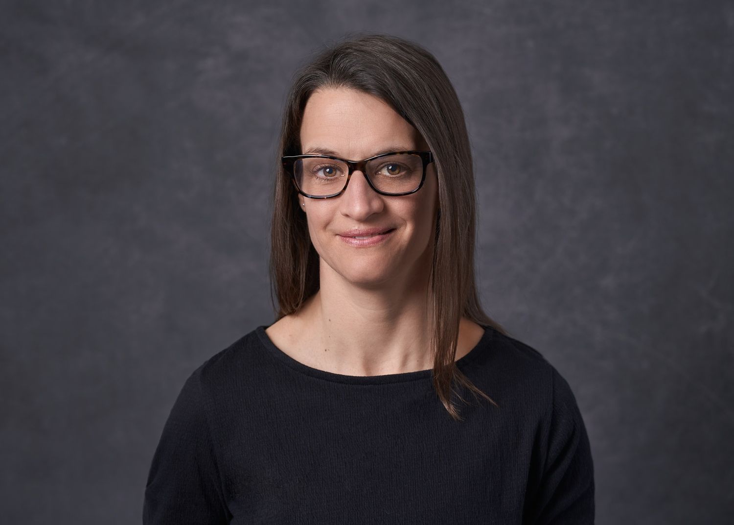 Headshot of 30-something female with glasses in black sweater