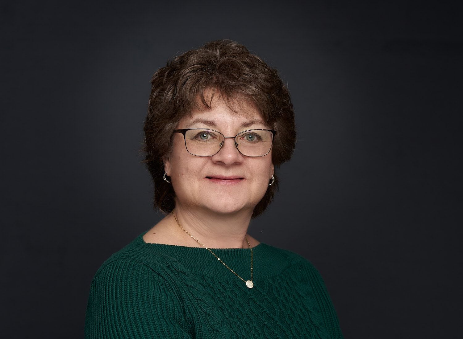 Middle-aged woman headshot in green sweater with reddish-brown hair