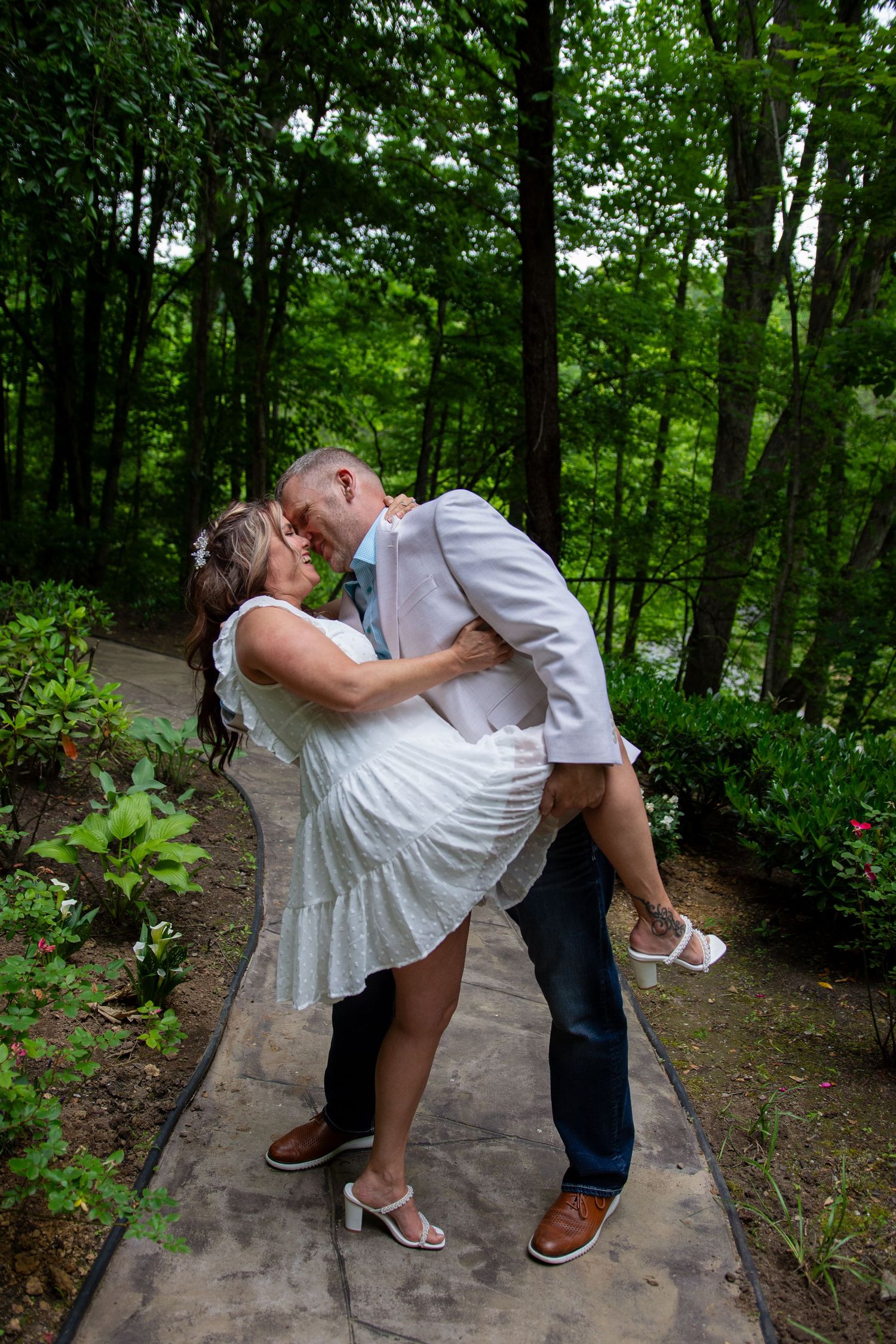 A romantic dip pose sequence on a wooded forest path showing a couple in wedding attire sharing intimate moments.