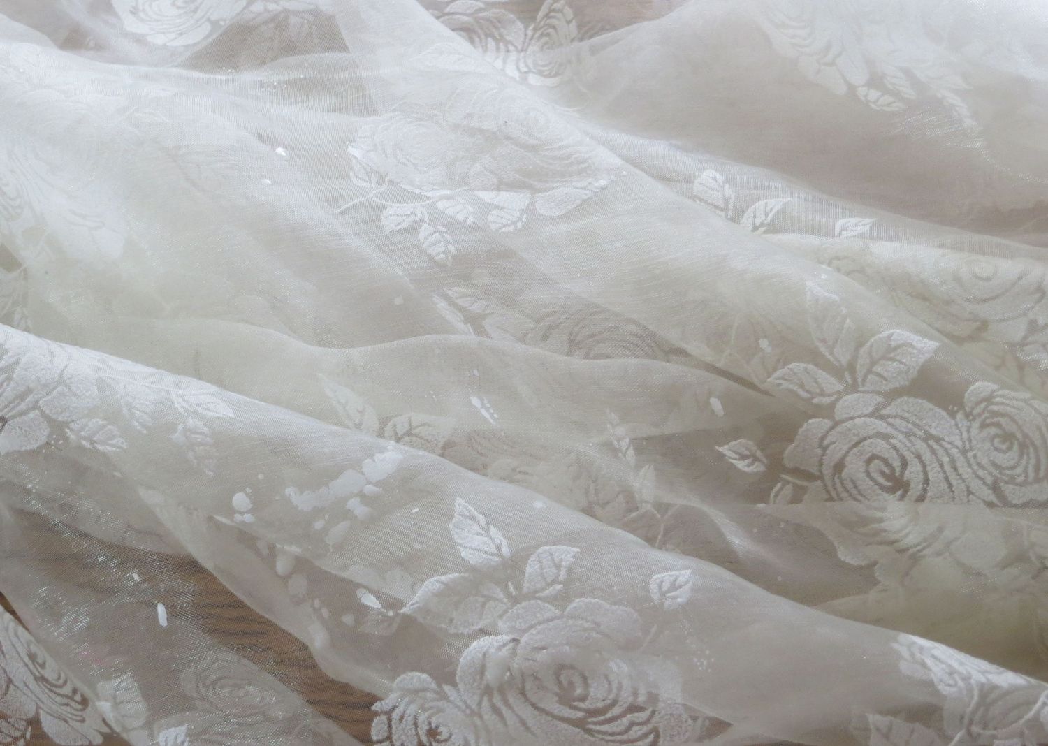 Delicate white lace fabric with floral patterns creates an elegant textural background for wedding or bridal design.