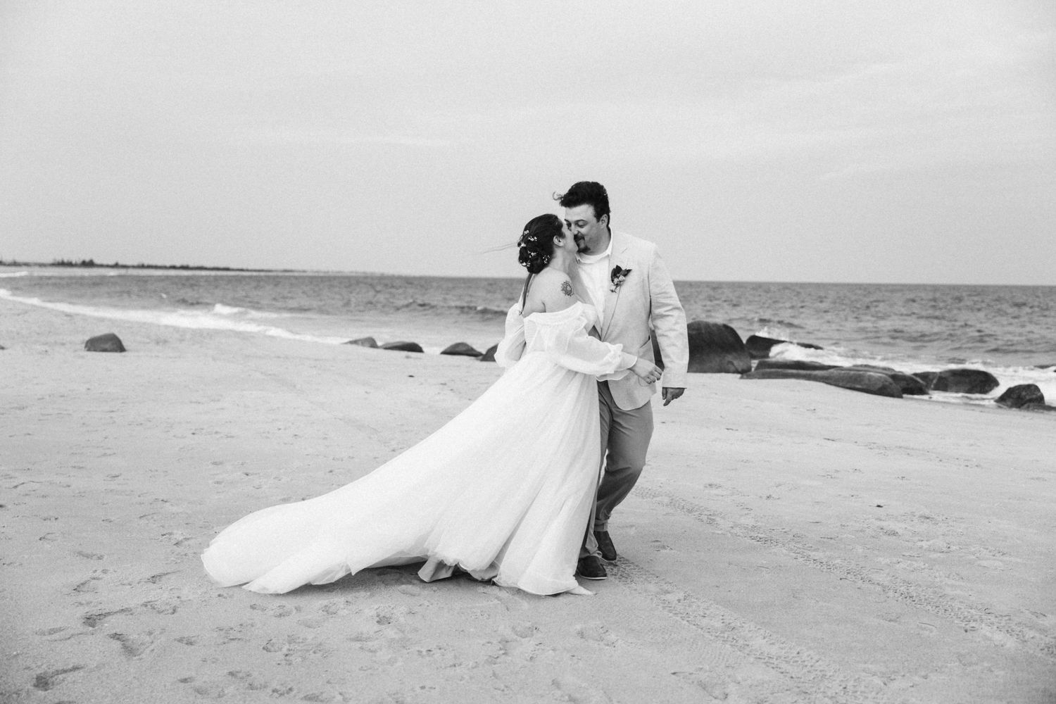 Romantic beach photoshoot sequence in black and white showing couple on sandy shoreline.