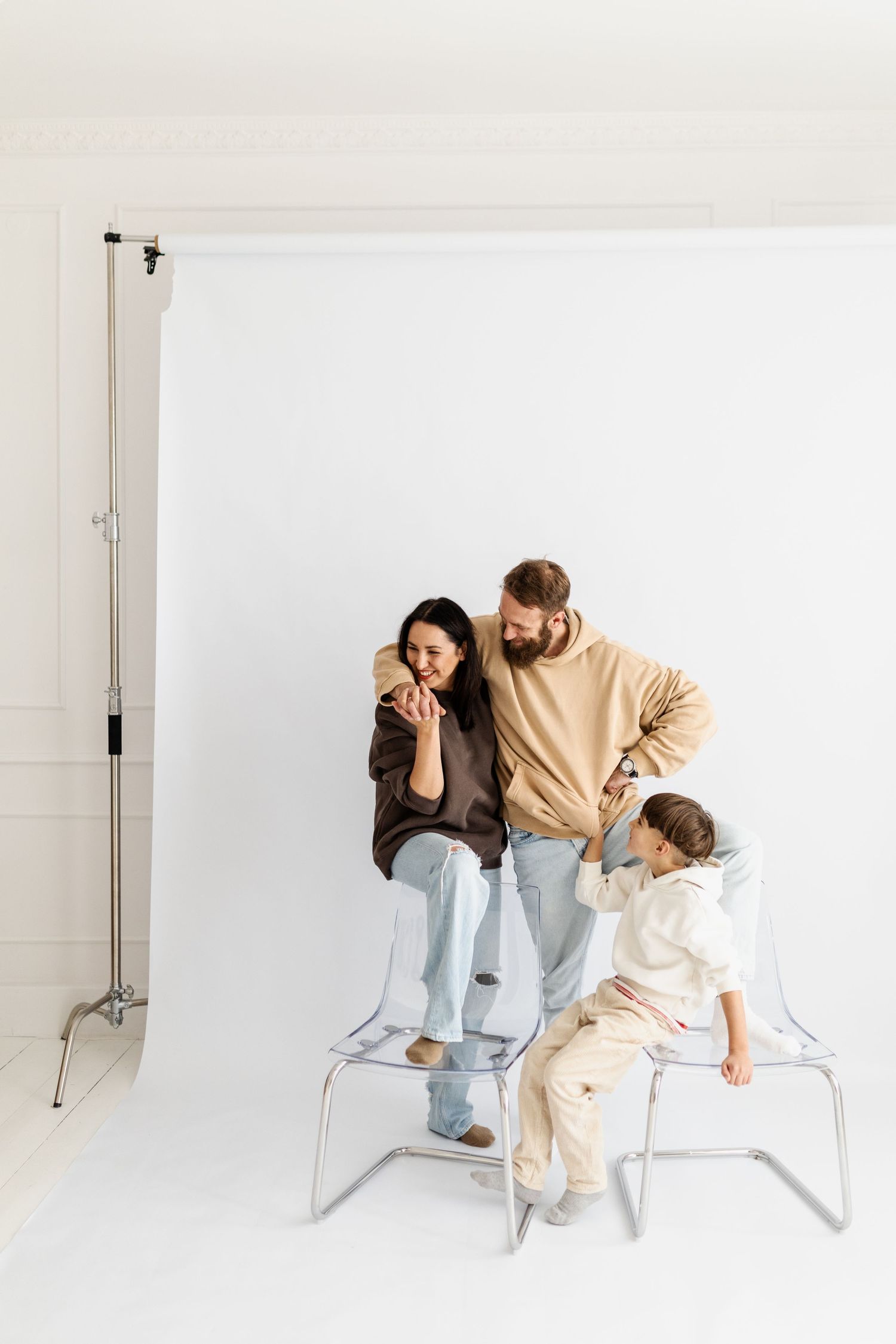 Family sitting together on a white bench in a photography studio setting.