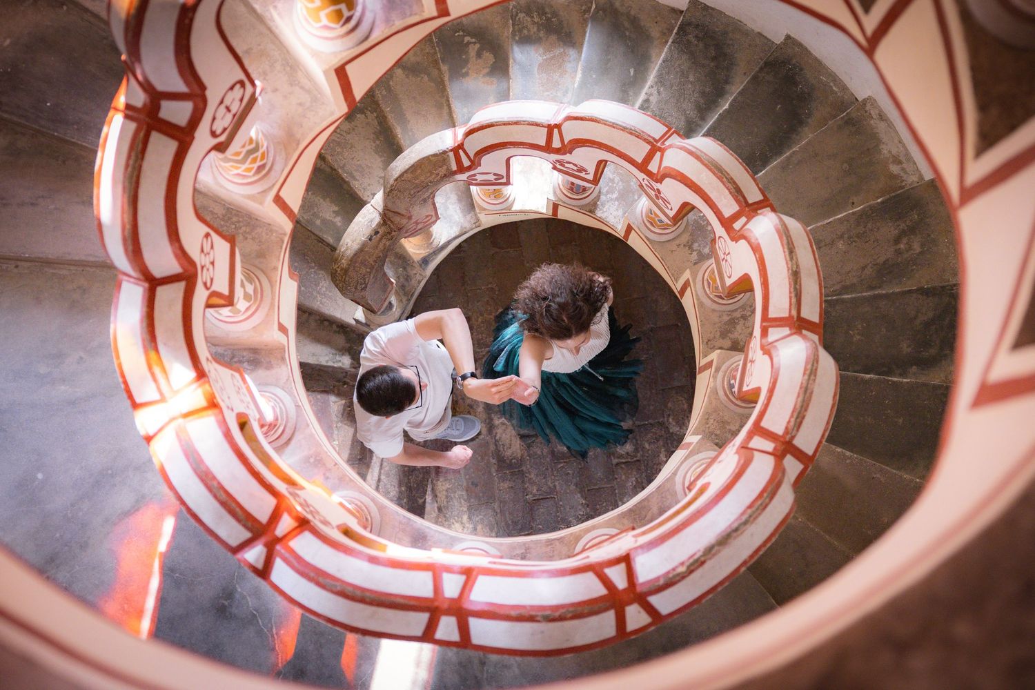 Spiral stone staircase interior with ornate architectural details and warm lighting.