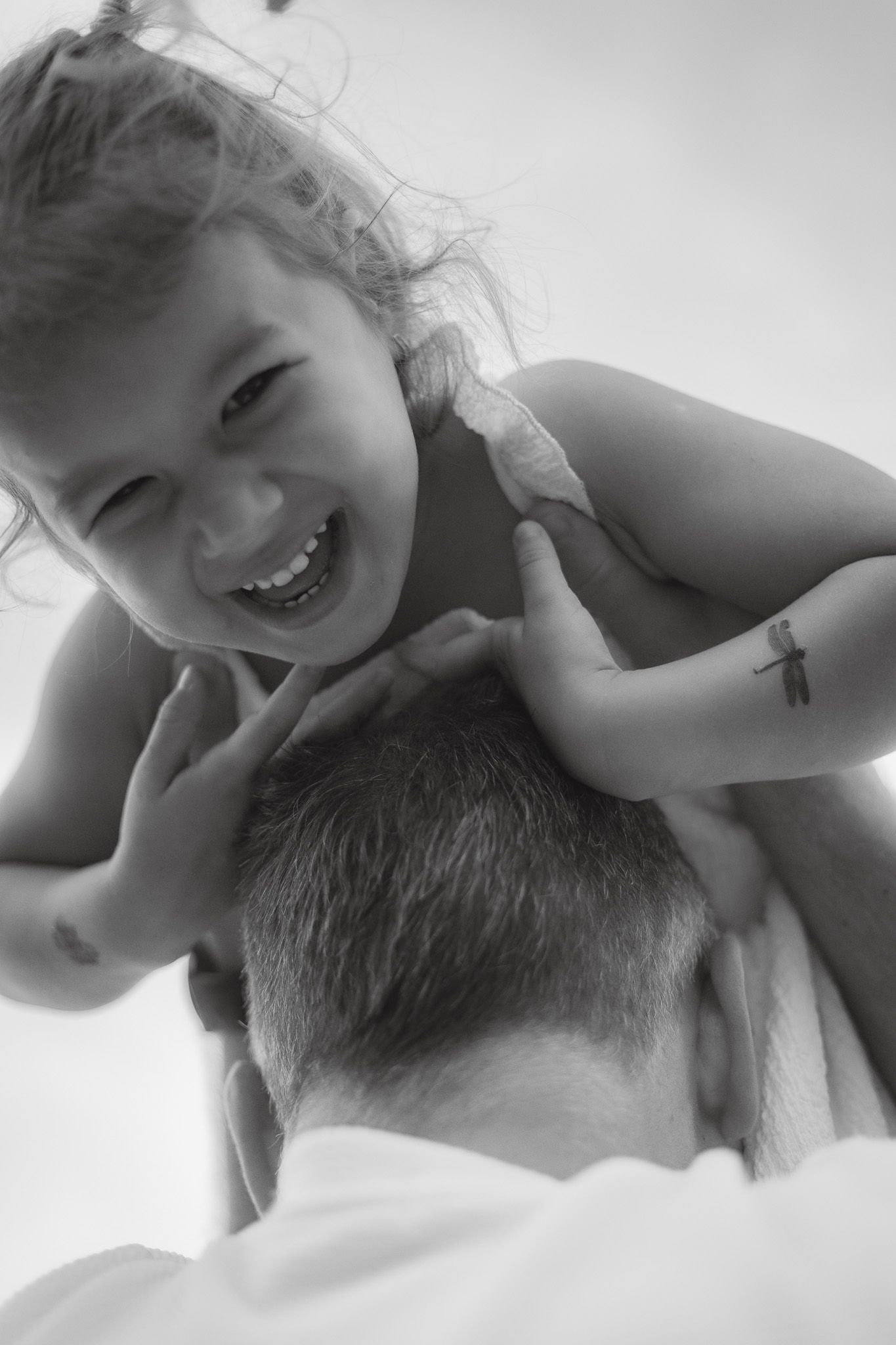 A playful black and white portrait capturing a joyful moment between parent and child.