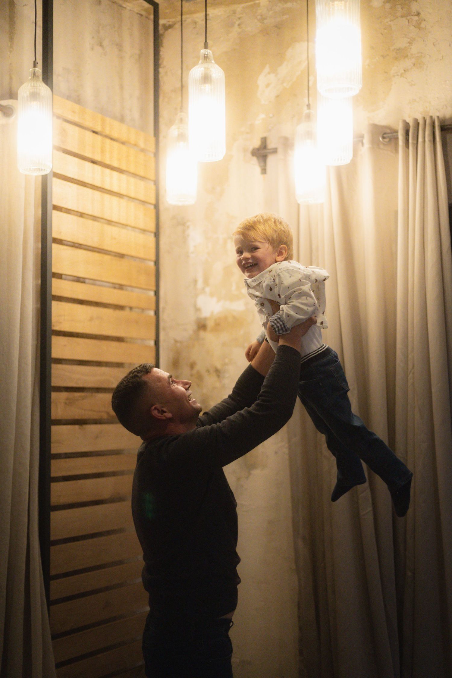 A heartwarming moment of a parent lifting a child in a warmly lit room.