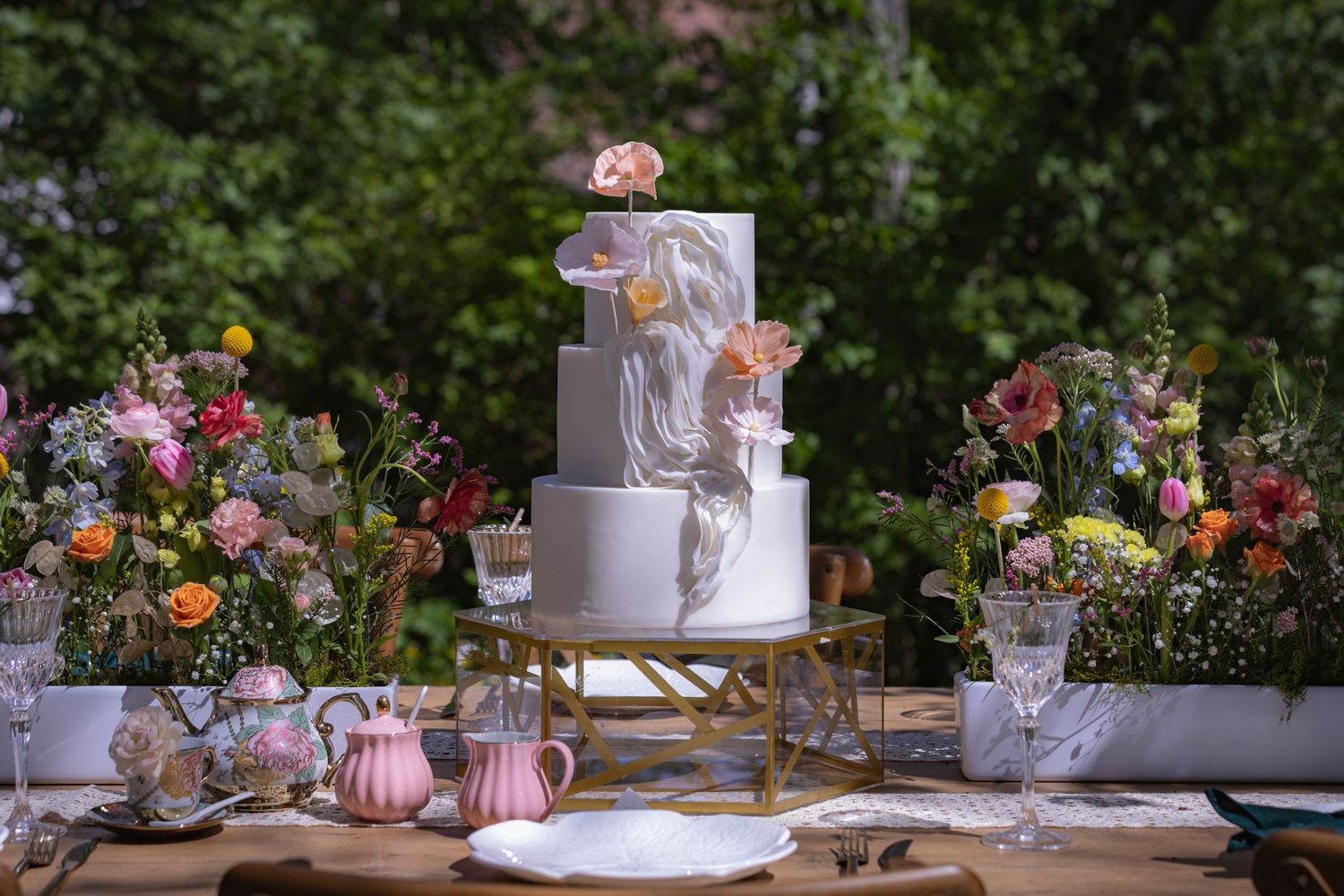 Elegant garden party table setting with colorful floral arrangements and pink accents.