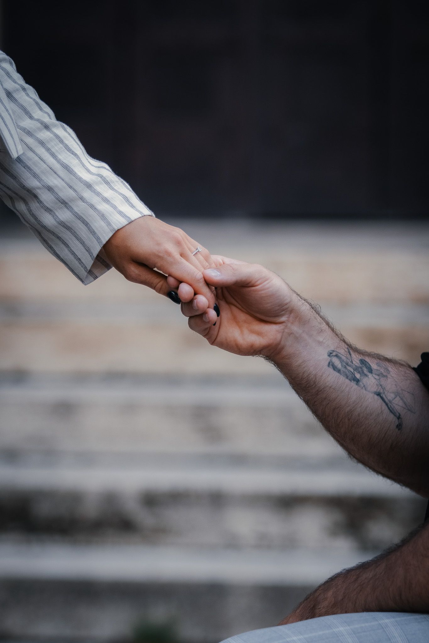 Close-up of intertwined hands showing connection and intimacy against dark background.