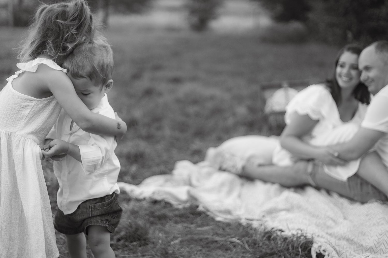 Family enjoying quality time together on a picnic blanket outdoors in monochrome.