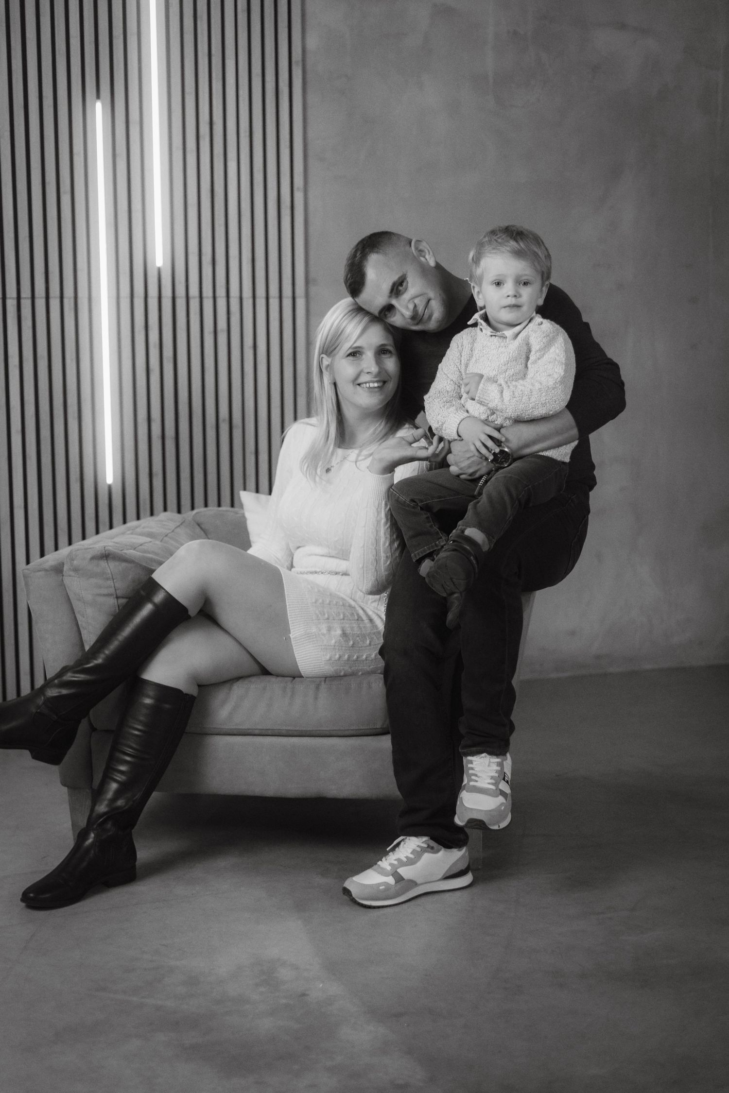 A casual studio portrait of a family relaxing together on a modern couch.