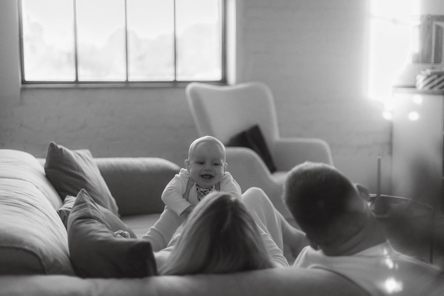 A tender black and white moment of family bonding on a cozy living room couch.