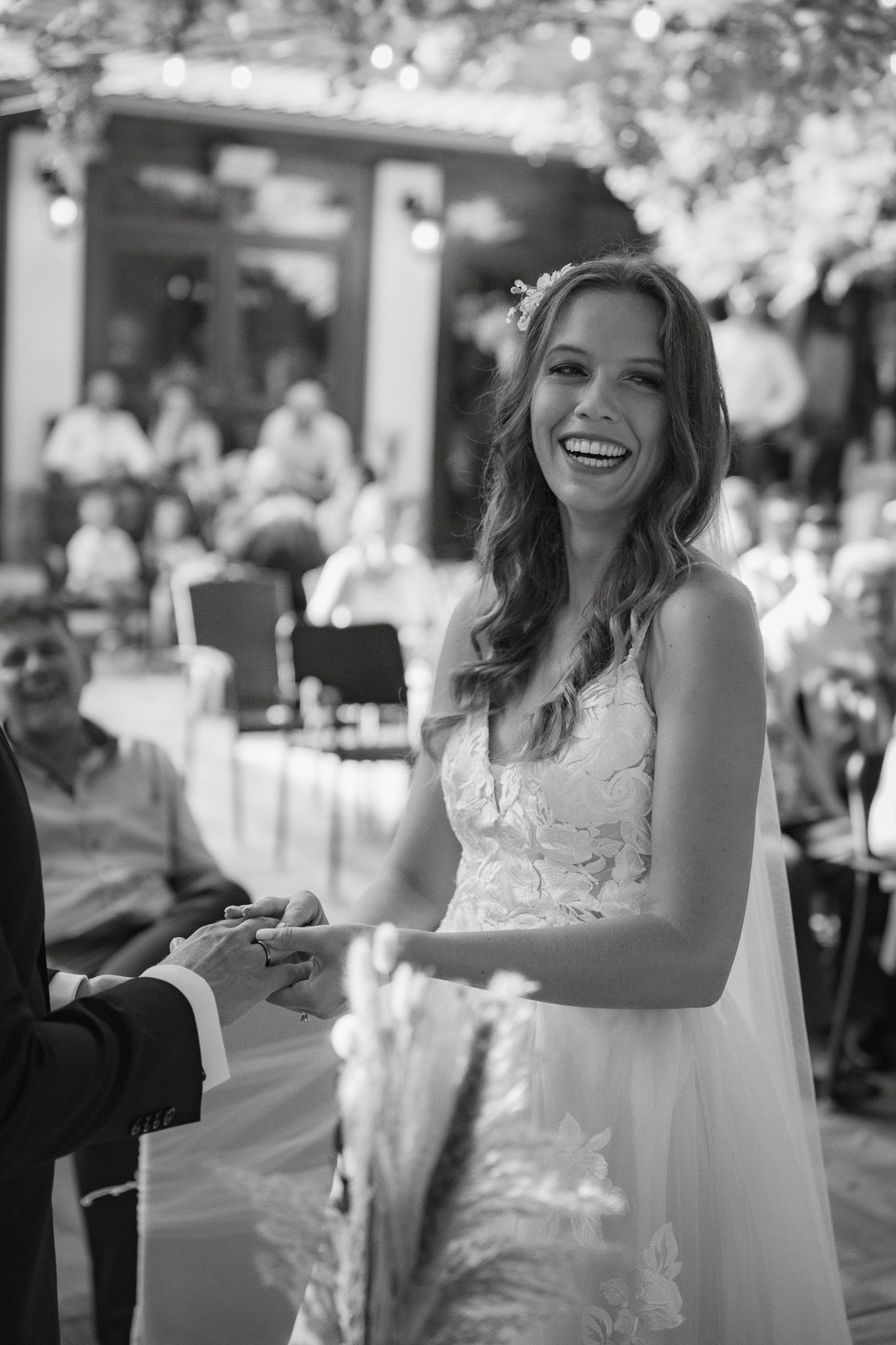 Four black and white wedding photos show a bride in a lace dress expressing joy and laughter at her reception celebration.