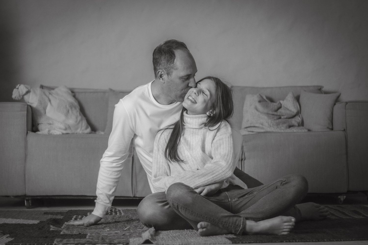 Couple sharing intimate moment on couch in black and white portrait.