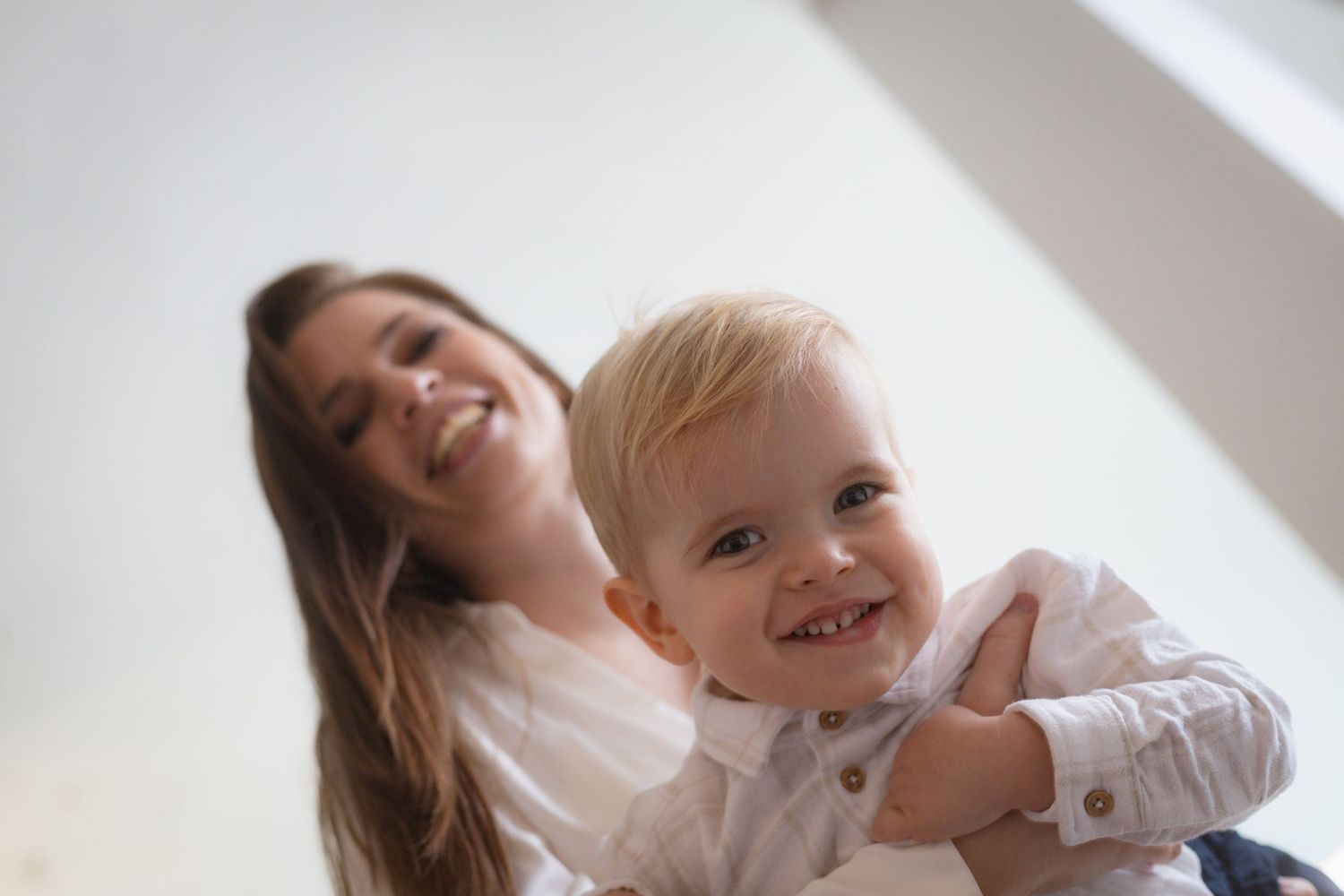 A joyful moment shared between a parent and child, both smiling and playing together.