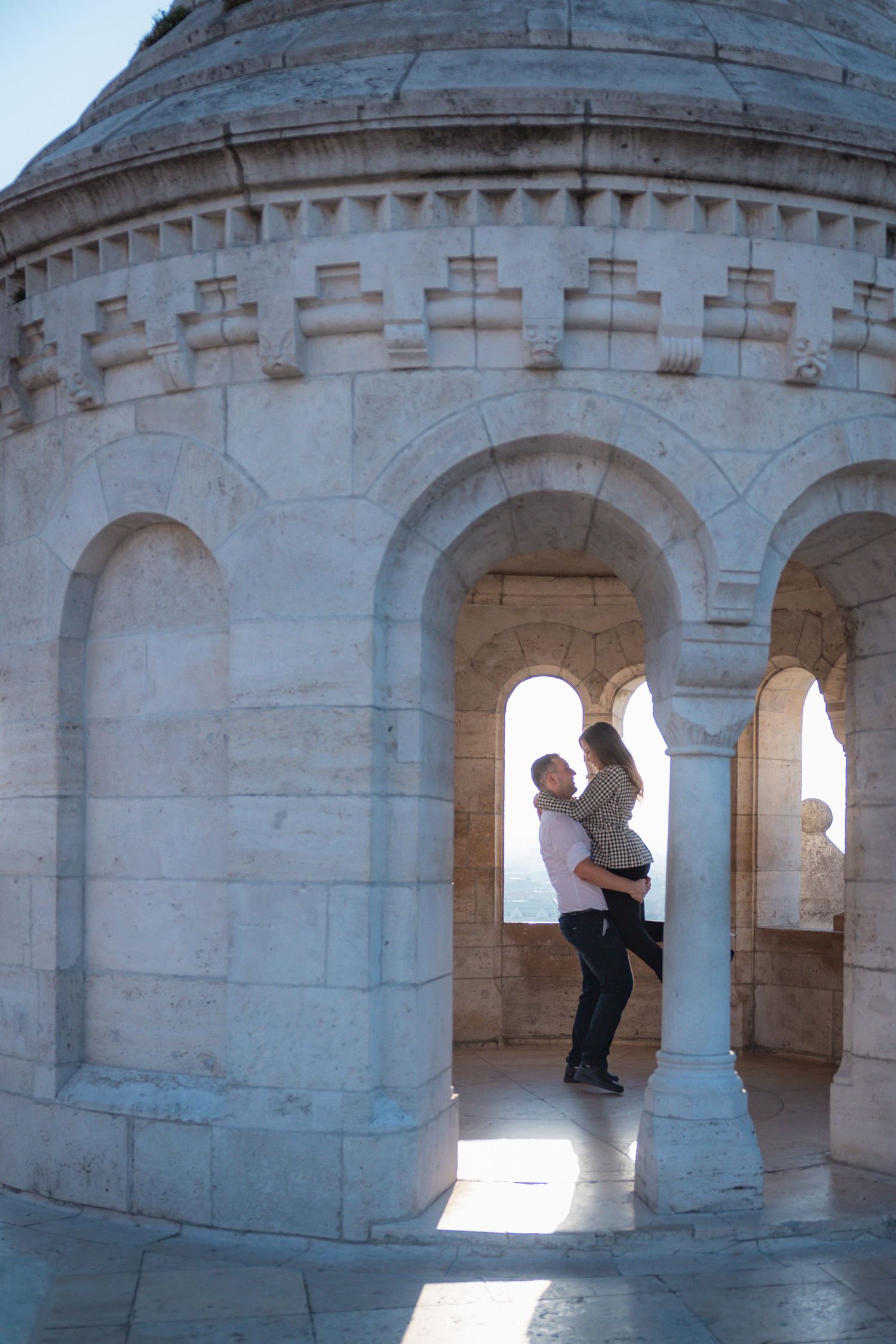 Romantic photoshoot in a stone archway with dramatic natural lighting and shadows.
