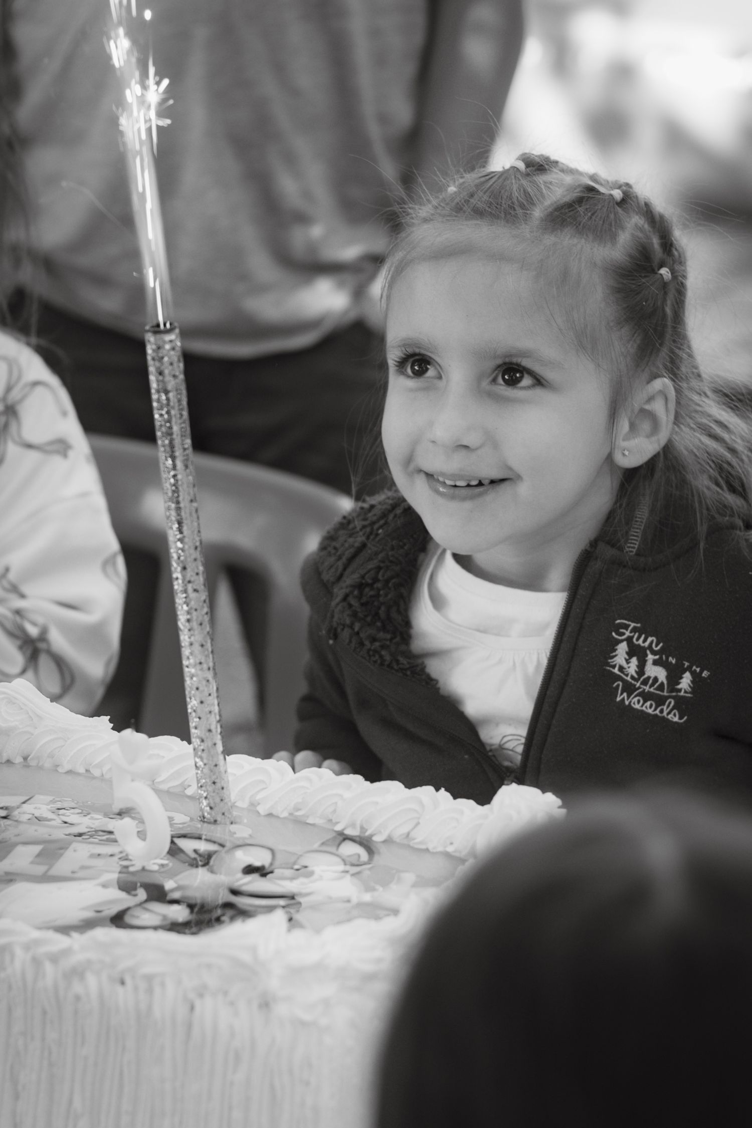 A young child gazing at a lit sparkler candle on a birthday cake during a celebration.