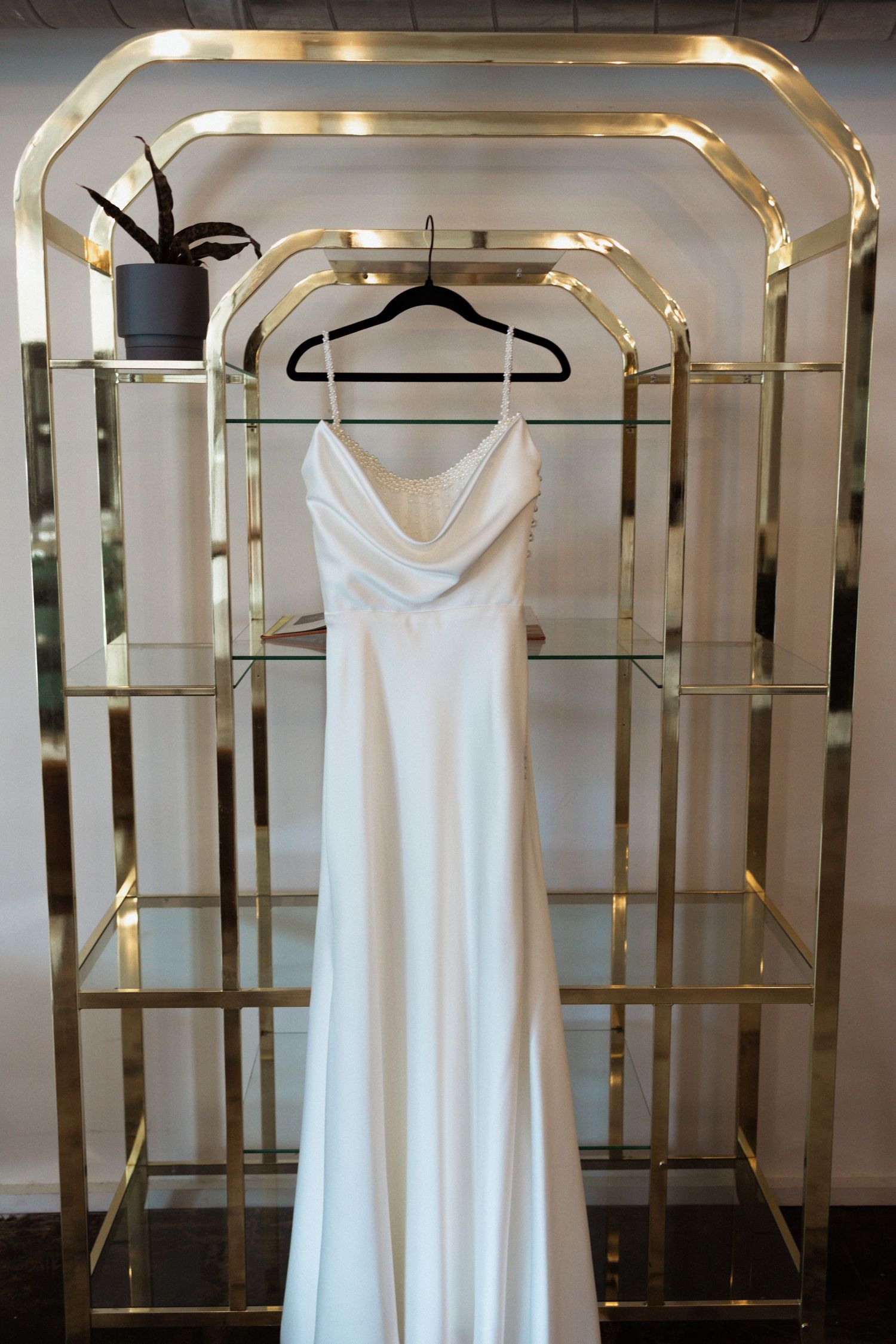 White sleeveless dresses displayed on gold clothing racks in an elegant retail setting.